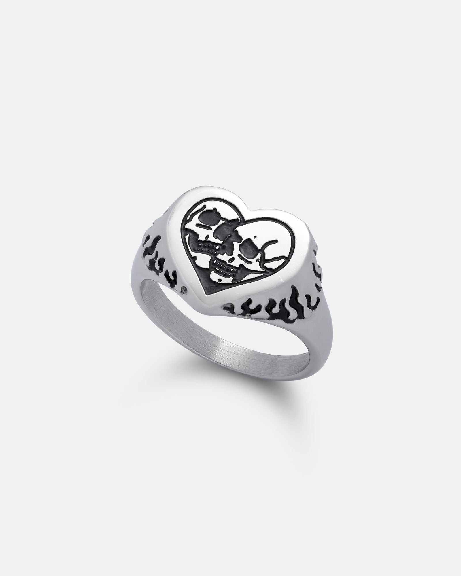 The Skull Heart Ring is a stainless steel gothic jewellery piece with a heart-shaped face featuring an engraved black skull and crossbones and side flame patterns, shown against a plain white background.