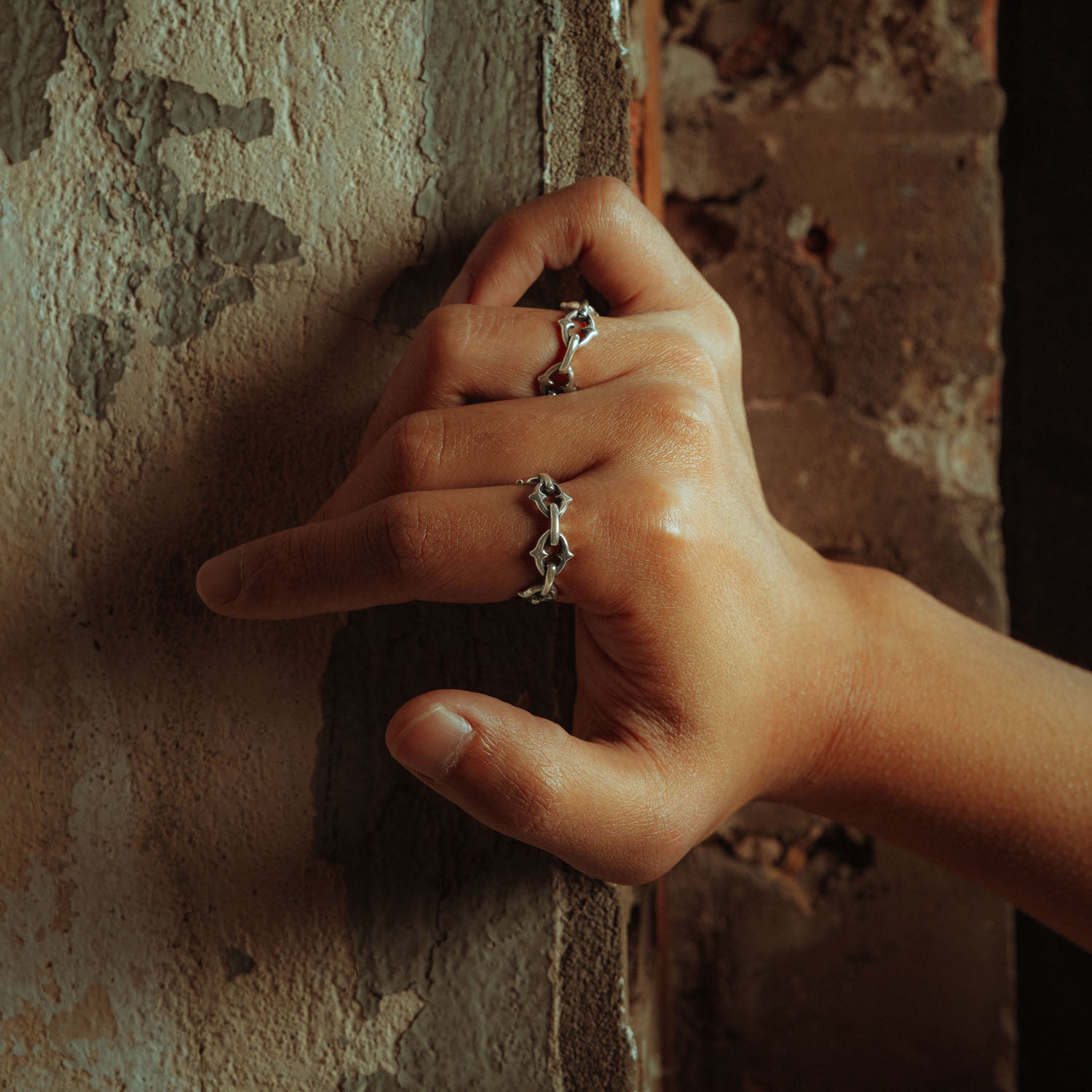 Sterling silver ring with spiked cable links  on male hand against wall