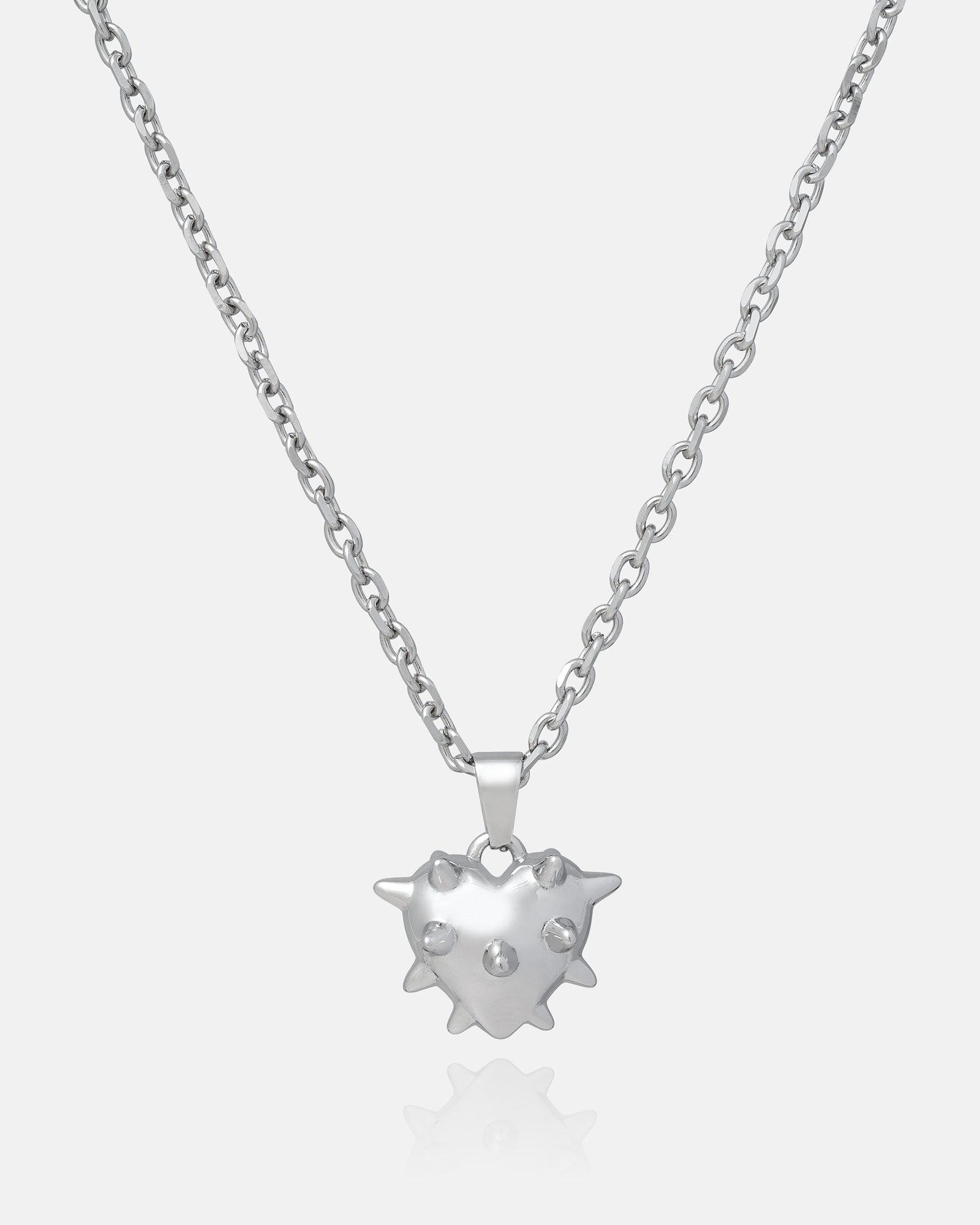 The Mini "Love Hurts" Spiked Heart Pendant is a silver stainless steel necklace with a glossy, spiked heart charm featuring three raised dots, displayed on a plain white background—ideal for statement jewelry lovers.