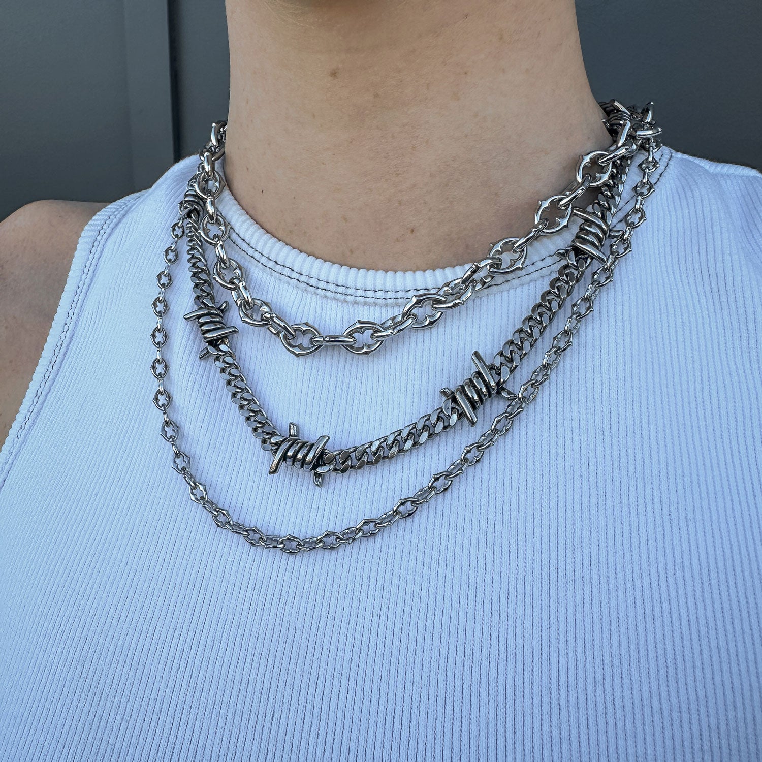 Gothic silver chain set with spiked and barbed wire jewelry on females neck by statement collective