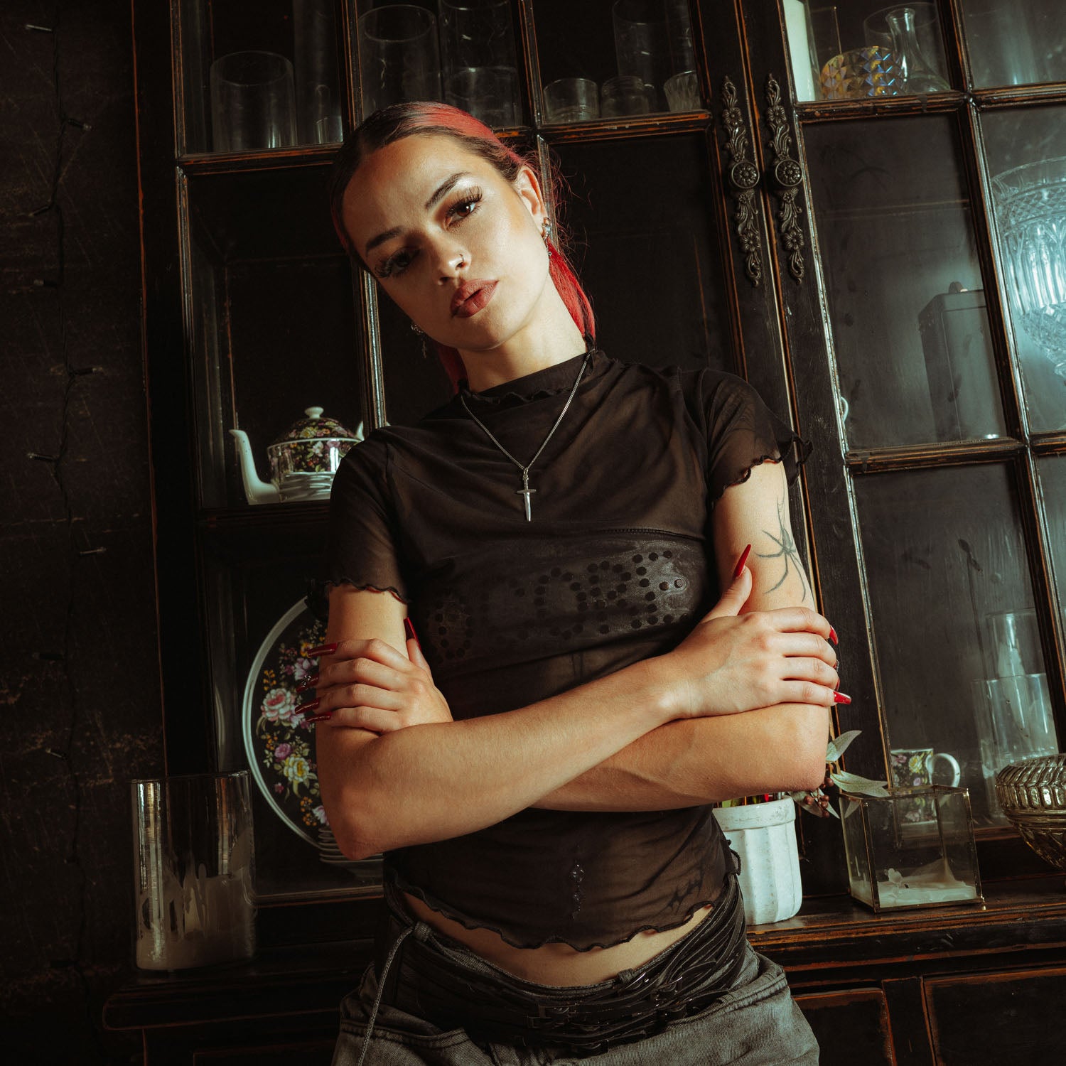 Silver chain with a dagger pendant on it, engraved with "Statement" on female model with red hair and tattoos