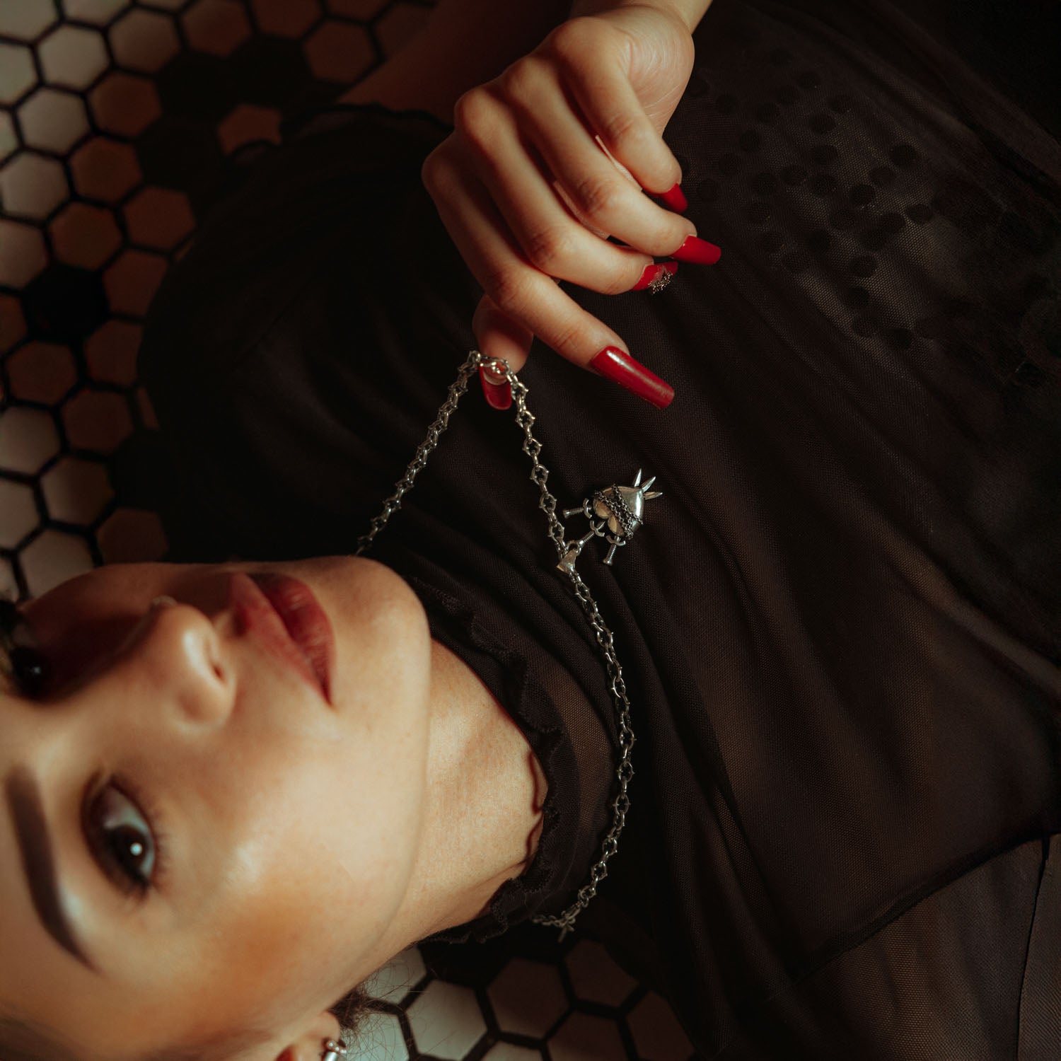 Silver heart pendant with three swords going through it and chain wrapped around it on a spiked chain on female model with black mesh shirt