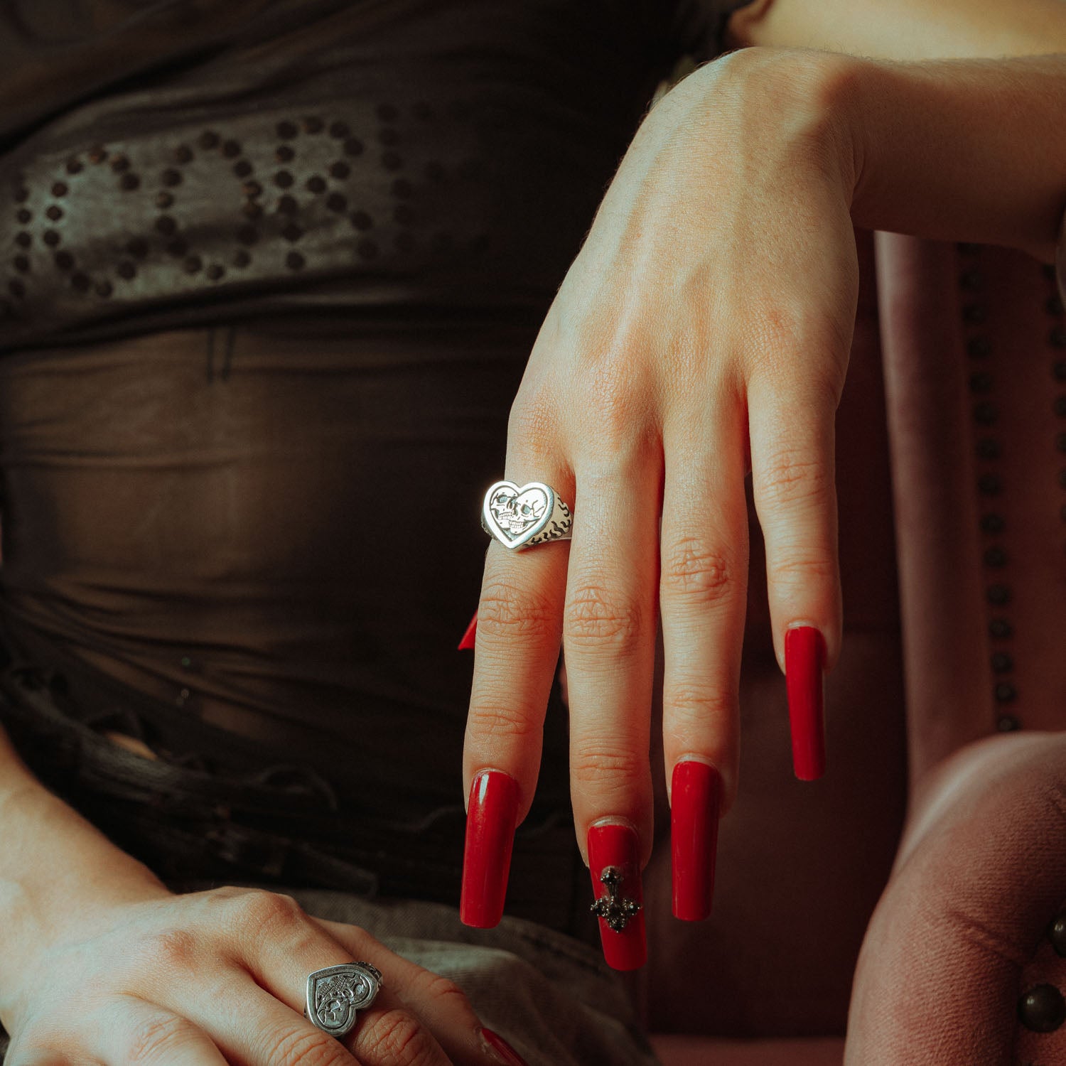 Sterling Silver heart shaped ring with skulls and flames  on female hands with red nails