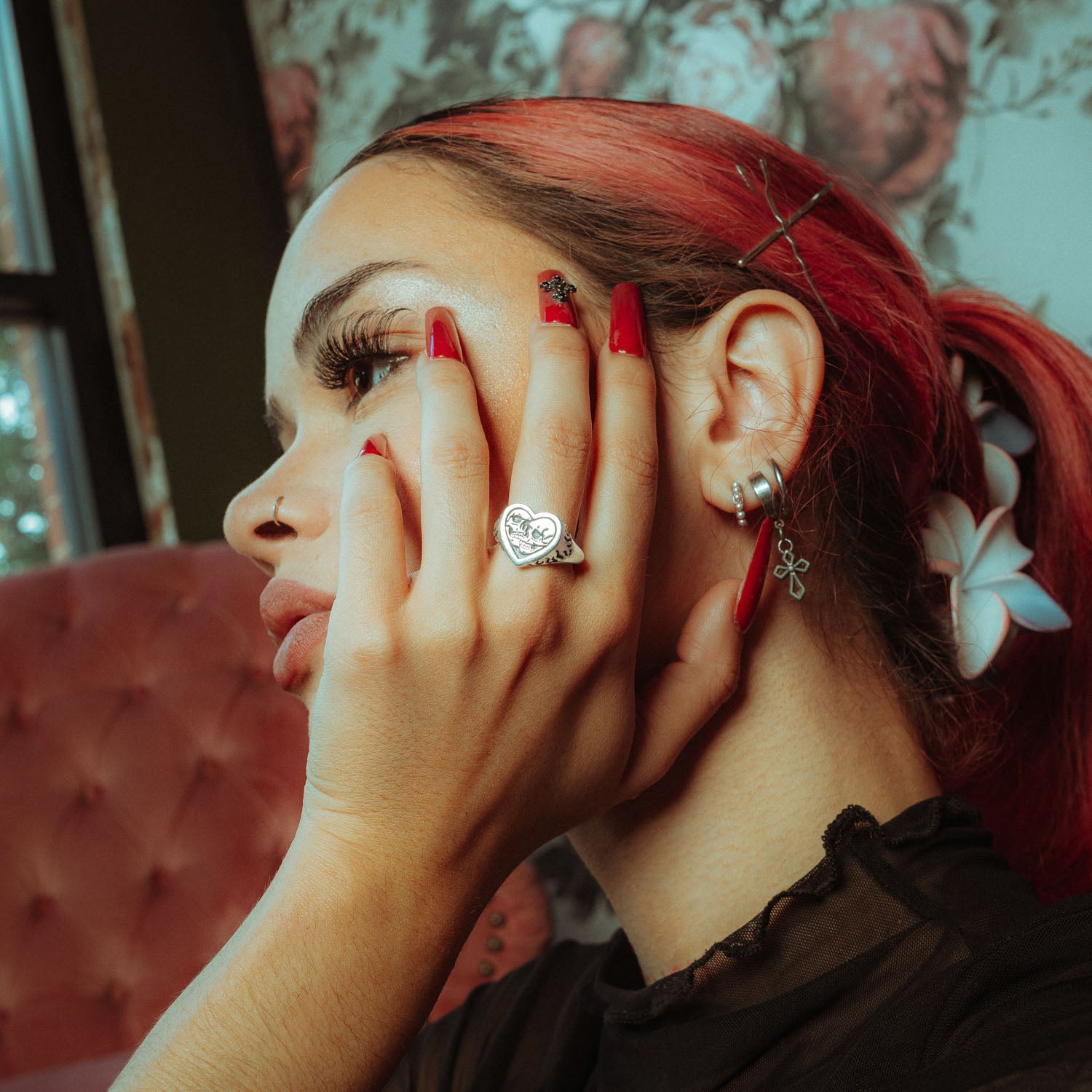 Sterling Silver heart shaped ring with skulls and flames on female model touching her face