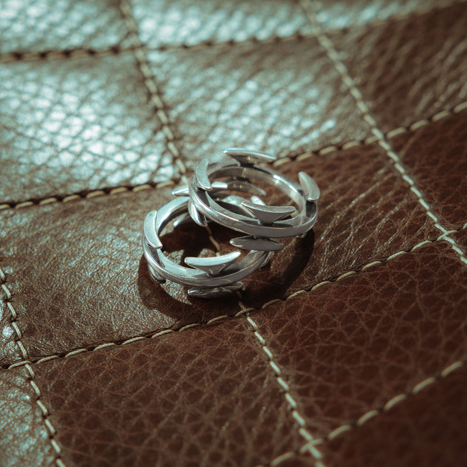 sterling silver razor wire rings stacked on top of each other on leather couch