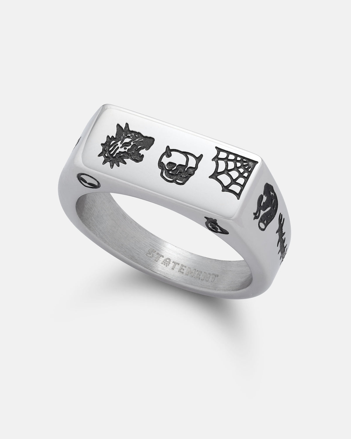 The STATEMENT Tattoo Signet Ring—a silver engraved piece featuring black designs of a wolf, a skull, a spider web, and a snake—is displayed on a plain white background.