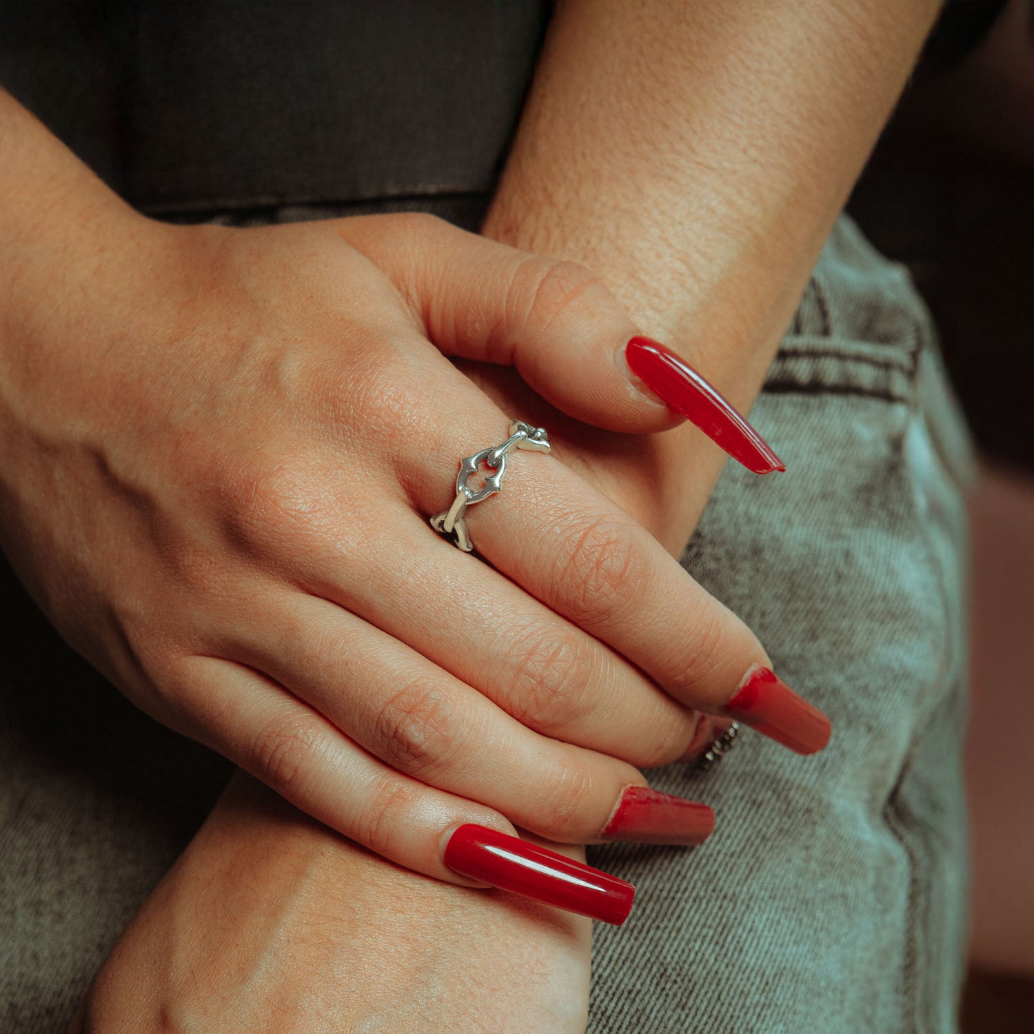 Sterling silver ring with spiked cable links on female hand with red nails