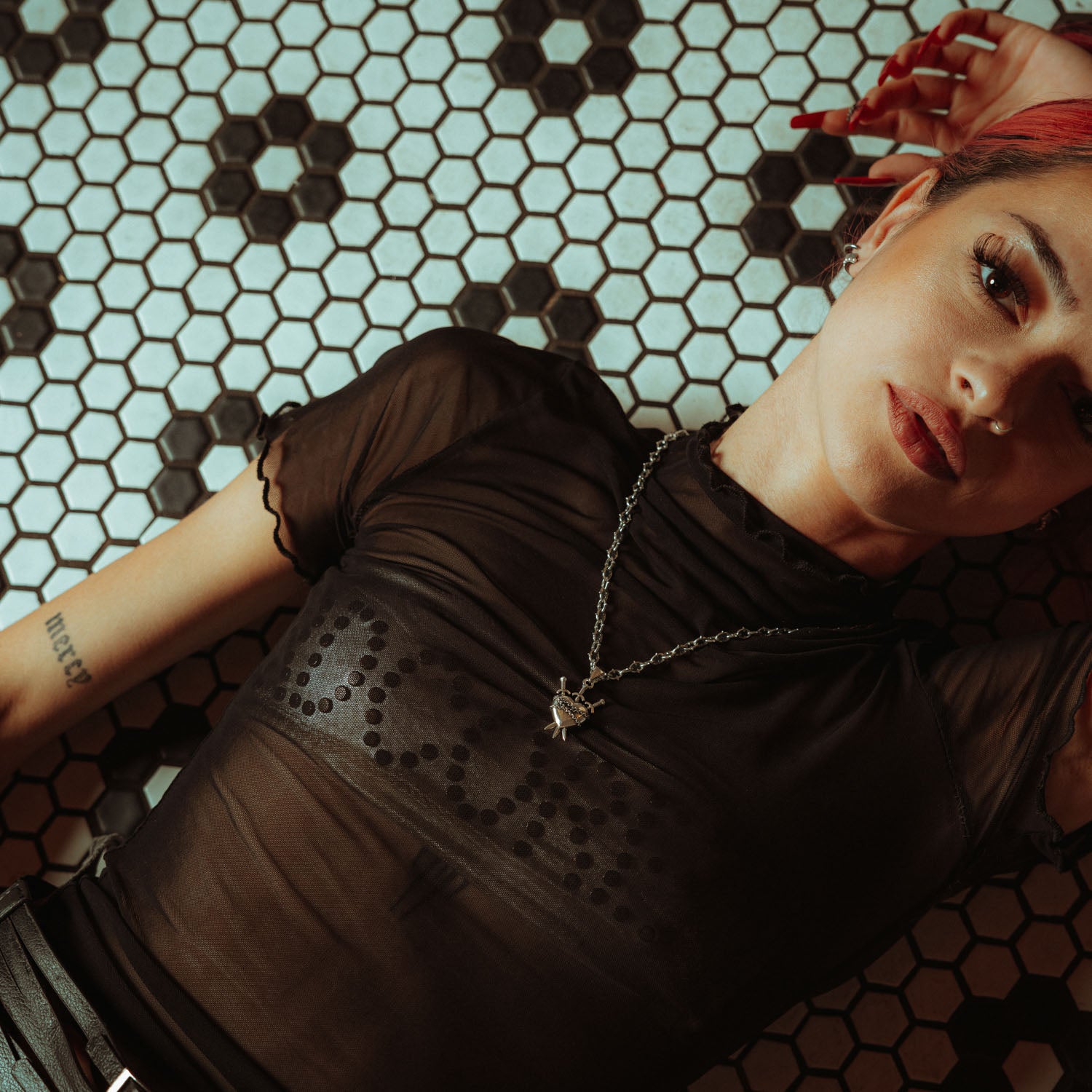 Silver heart pendant with three swords going through it and chain wrapped around it on a spiked chain. on female model with black mesh shirt on