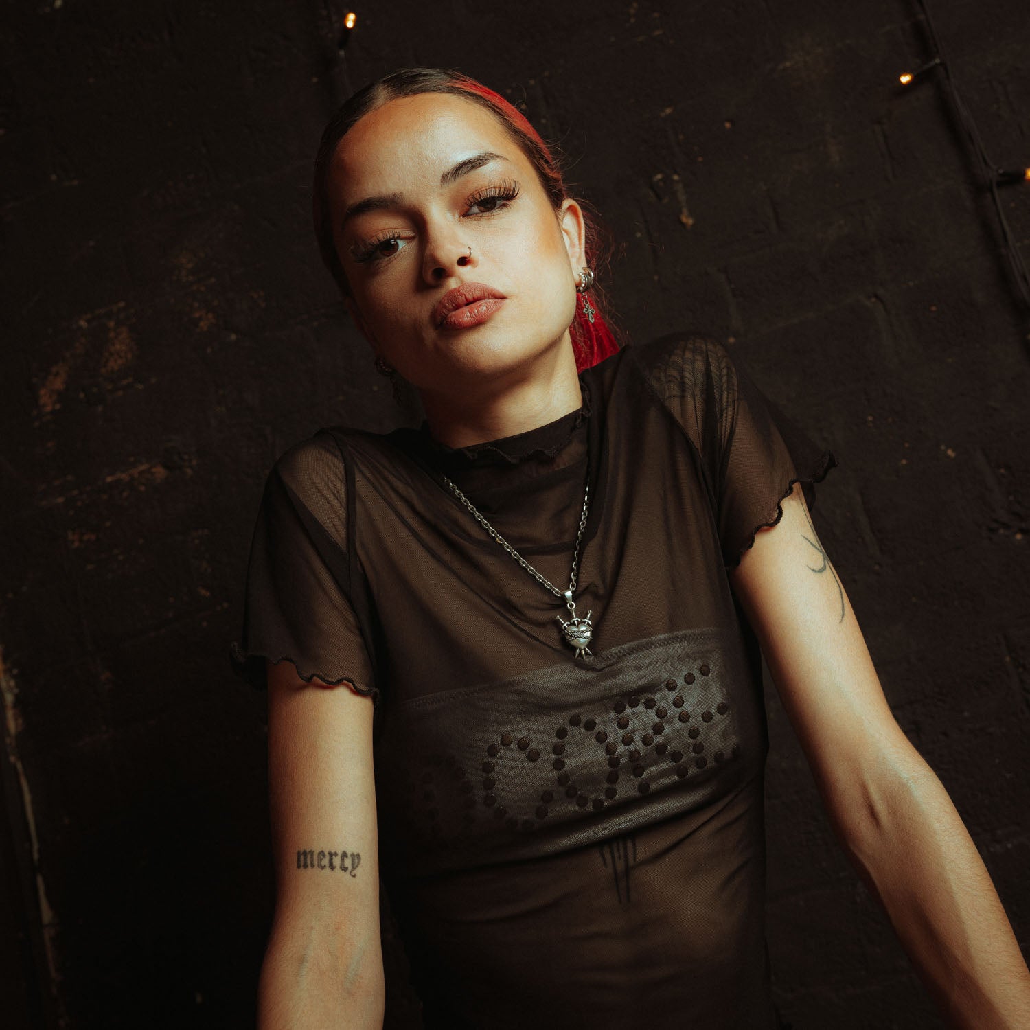 Silver heart pendant with 3 swords going through it and wrapped in chain on female model with black mesh shirt