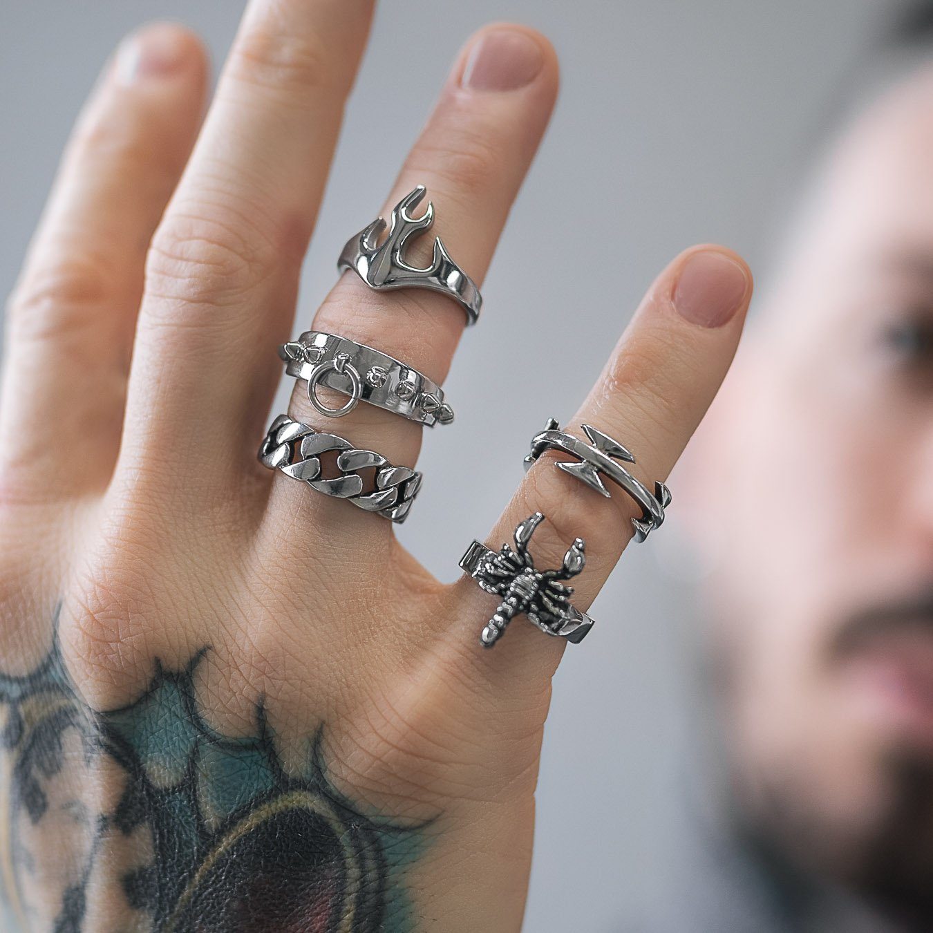 mens hand with tattoos and silver rings on fingers by statement collective