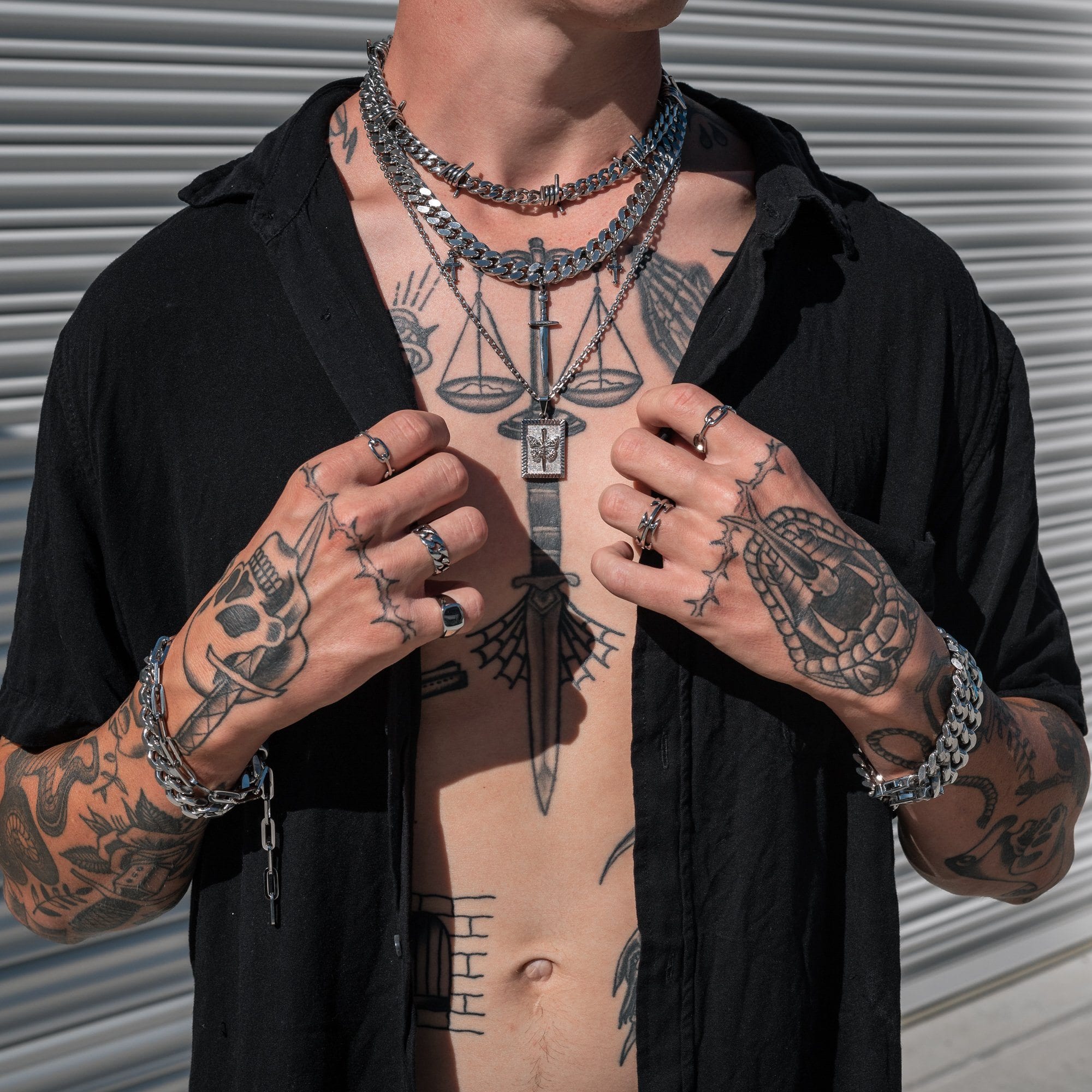 tattooed man with silver jewelry featuring butterfly pendant necklace by statement collective