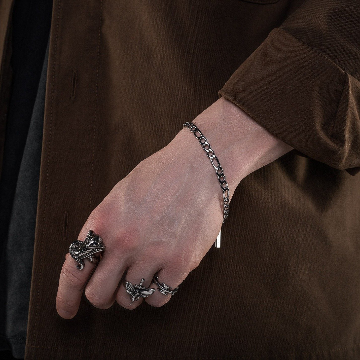 mens hand with silver figaro chain bracelet by statement