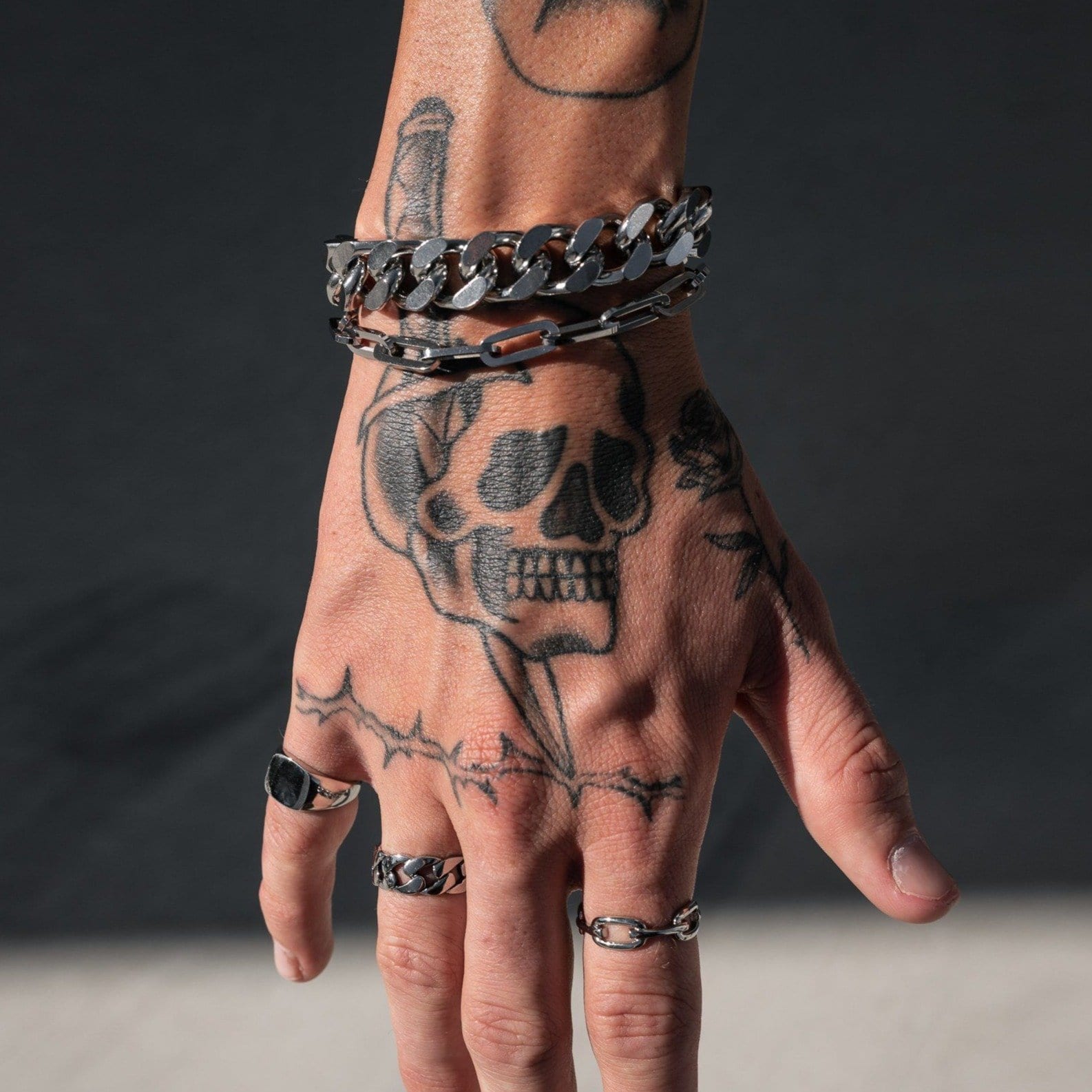 tattooed mens hand showing double chain bracelet by statement collective