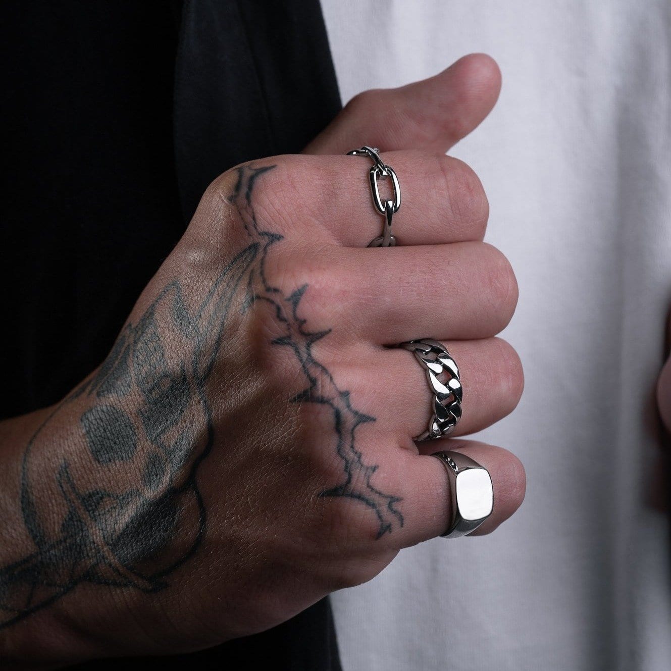 mens tattooed hand with silver cuban link ring
