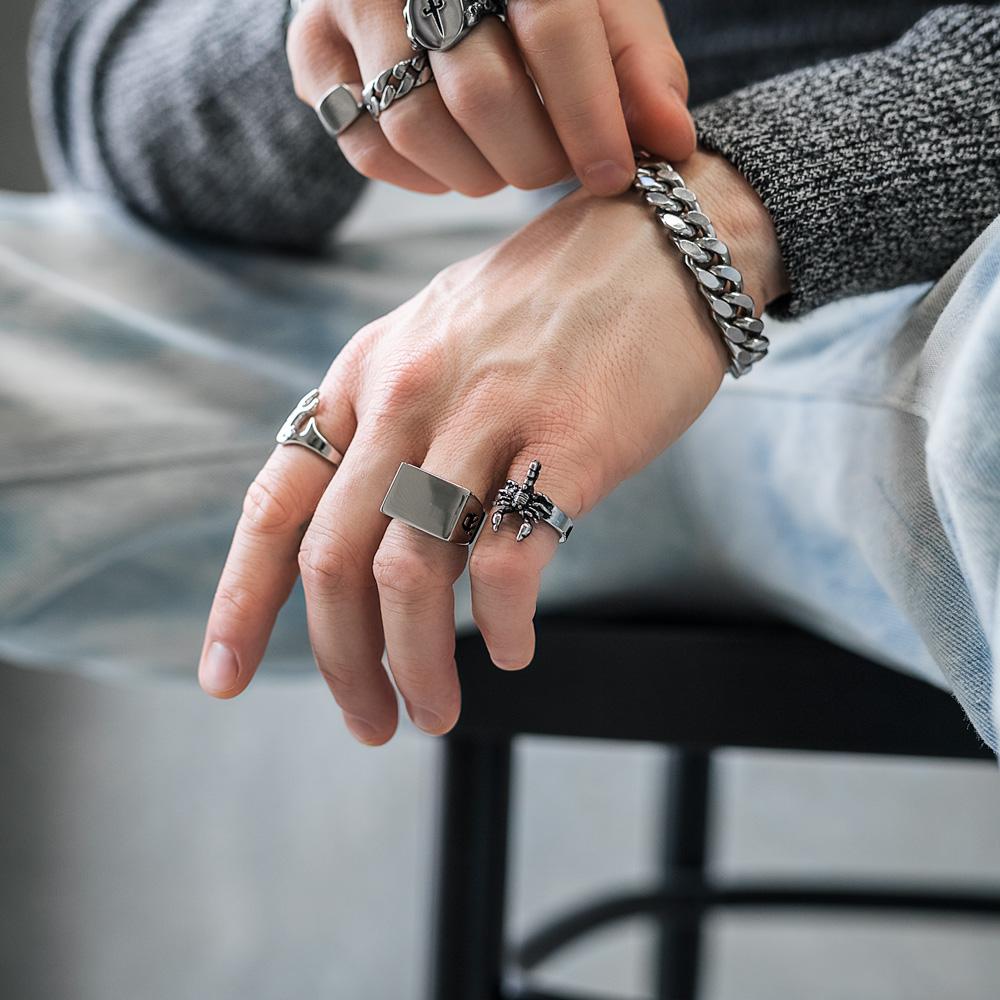 mens hand showcasing large signet ring wearing blue jeans