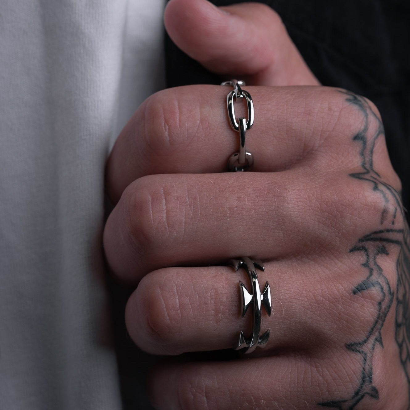 mens hand in dark studio wearing silver rings by statement collective