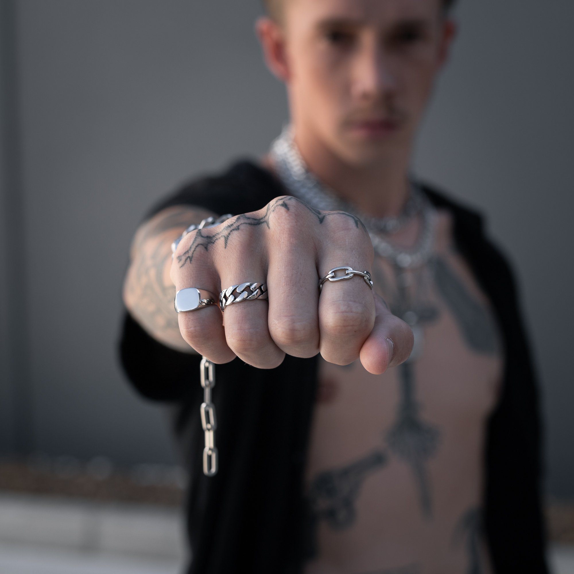 tattooed male model with silver rings on hand by statement collective