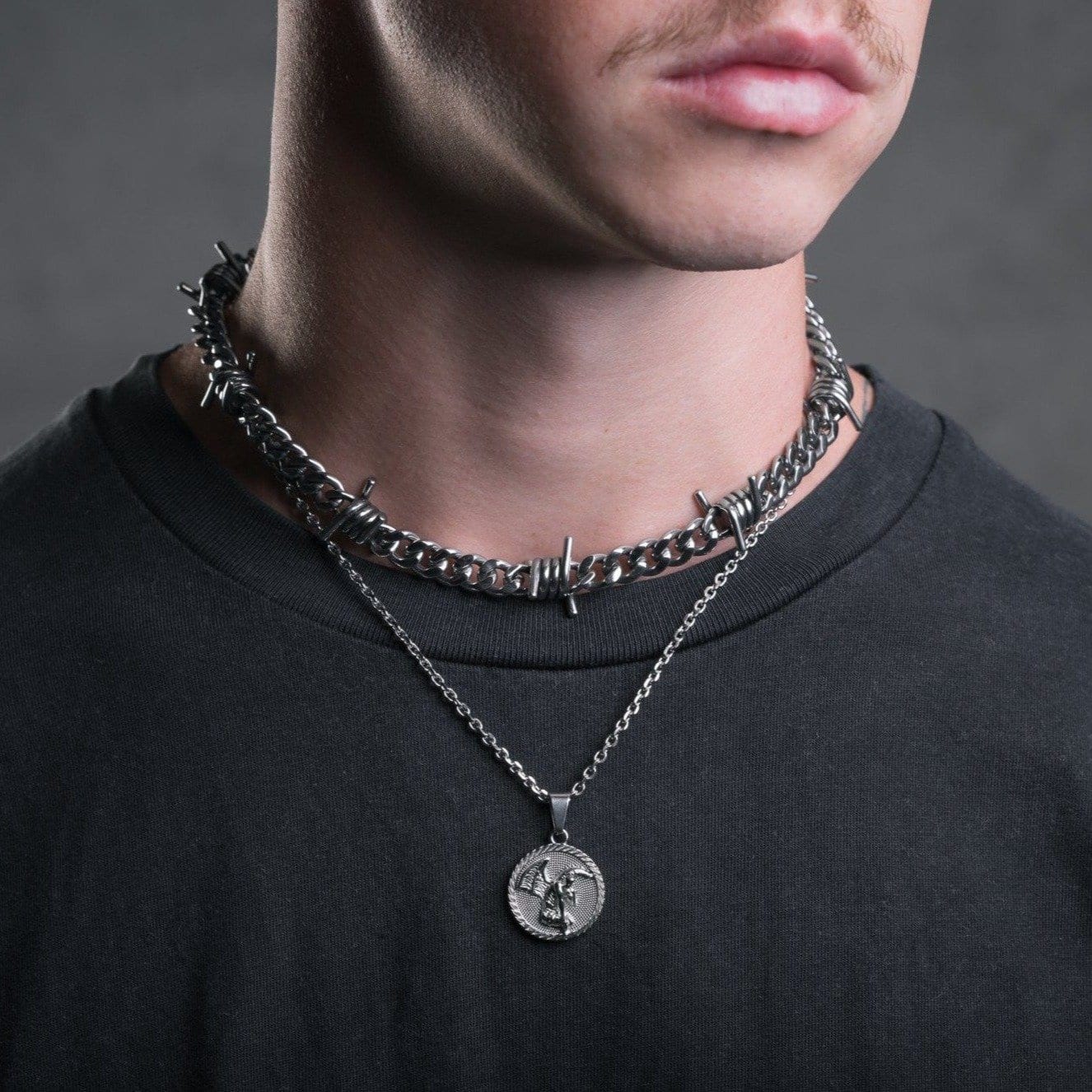 man with dark shirt wearing medallion necklace by statement collective