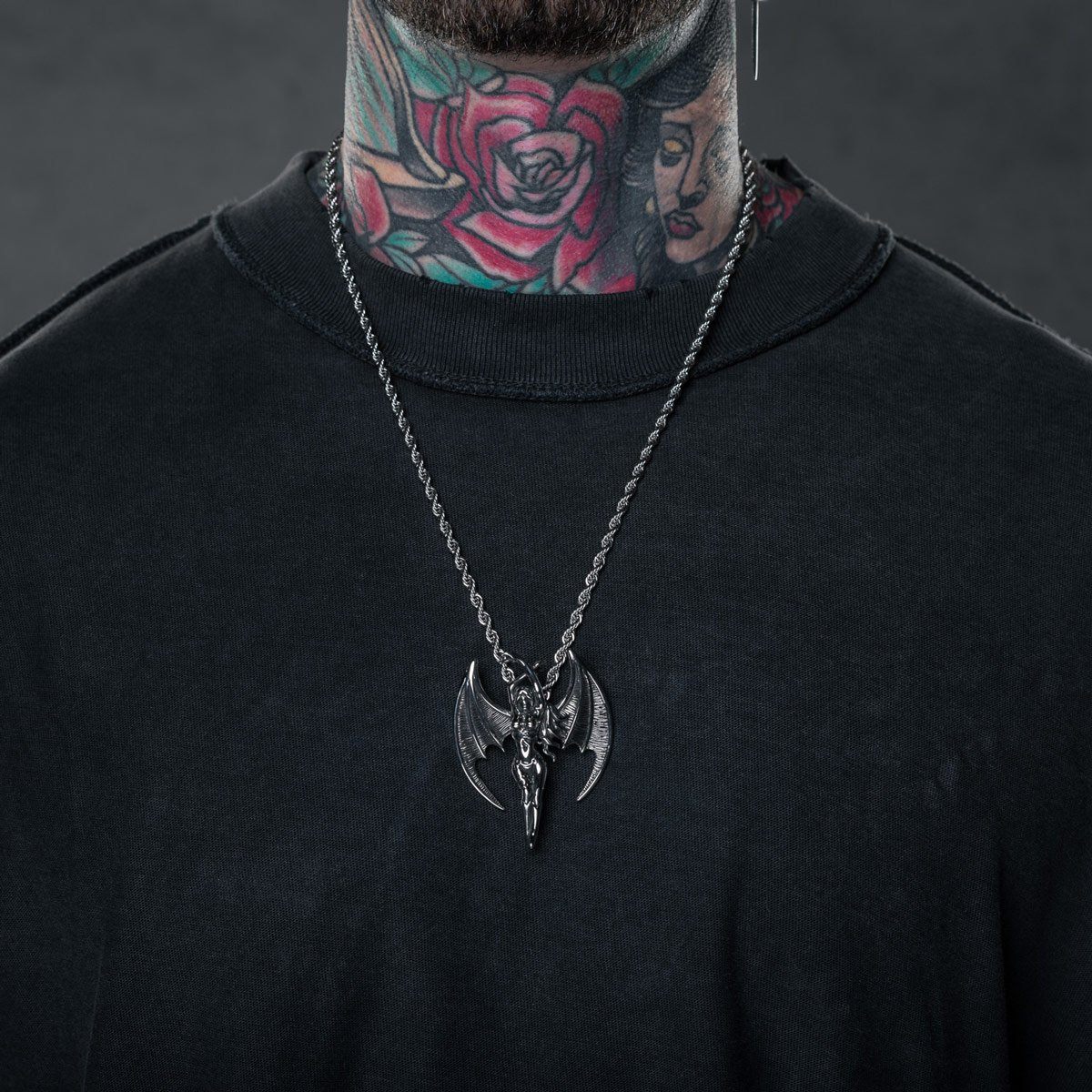man with tattooed neck wearing succubus pendant necklace and black shirt