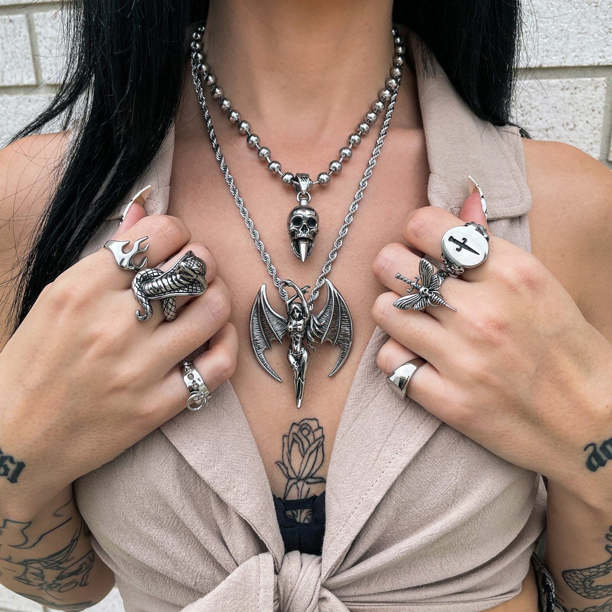 women with cream top wearing skull pendant necklace and rings