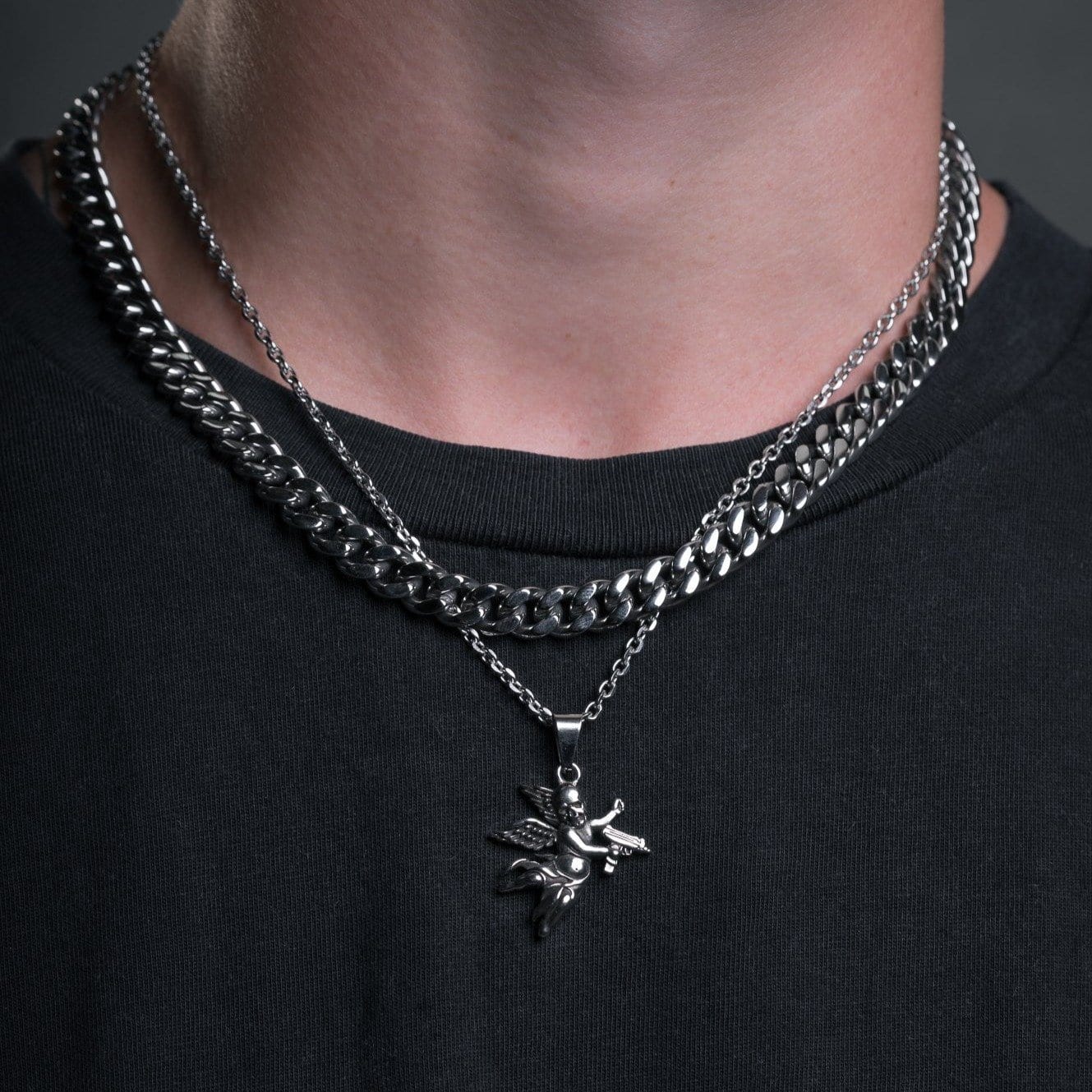 steel cupid pendant necklace with cuban chain on mens neck by statement collective