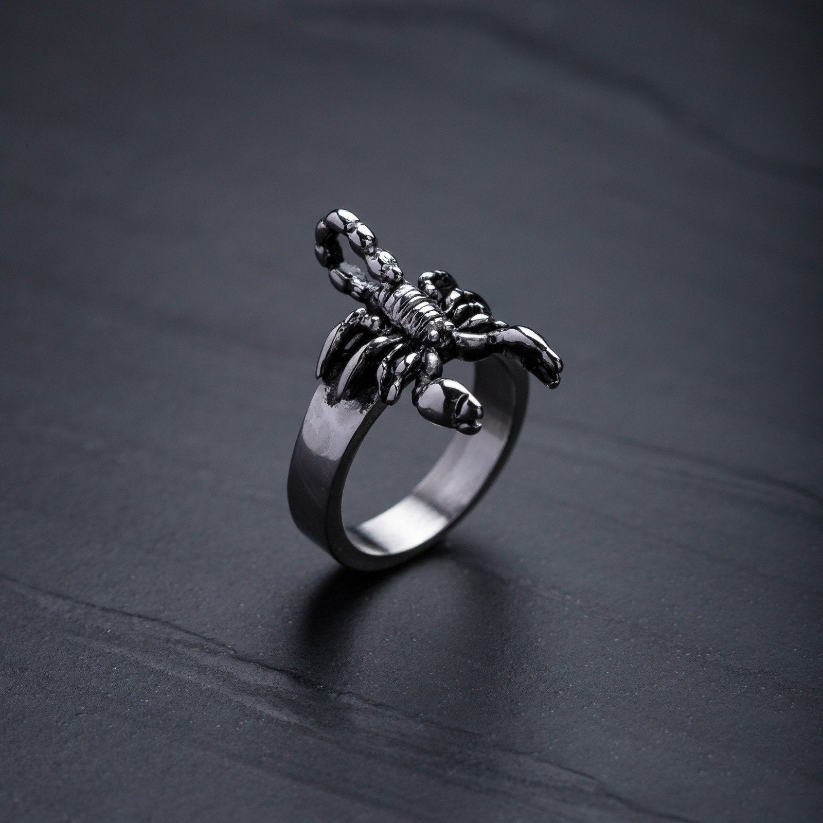 silver steel scorpion ring on dark stone background by statement