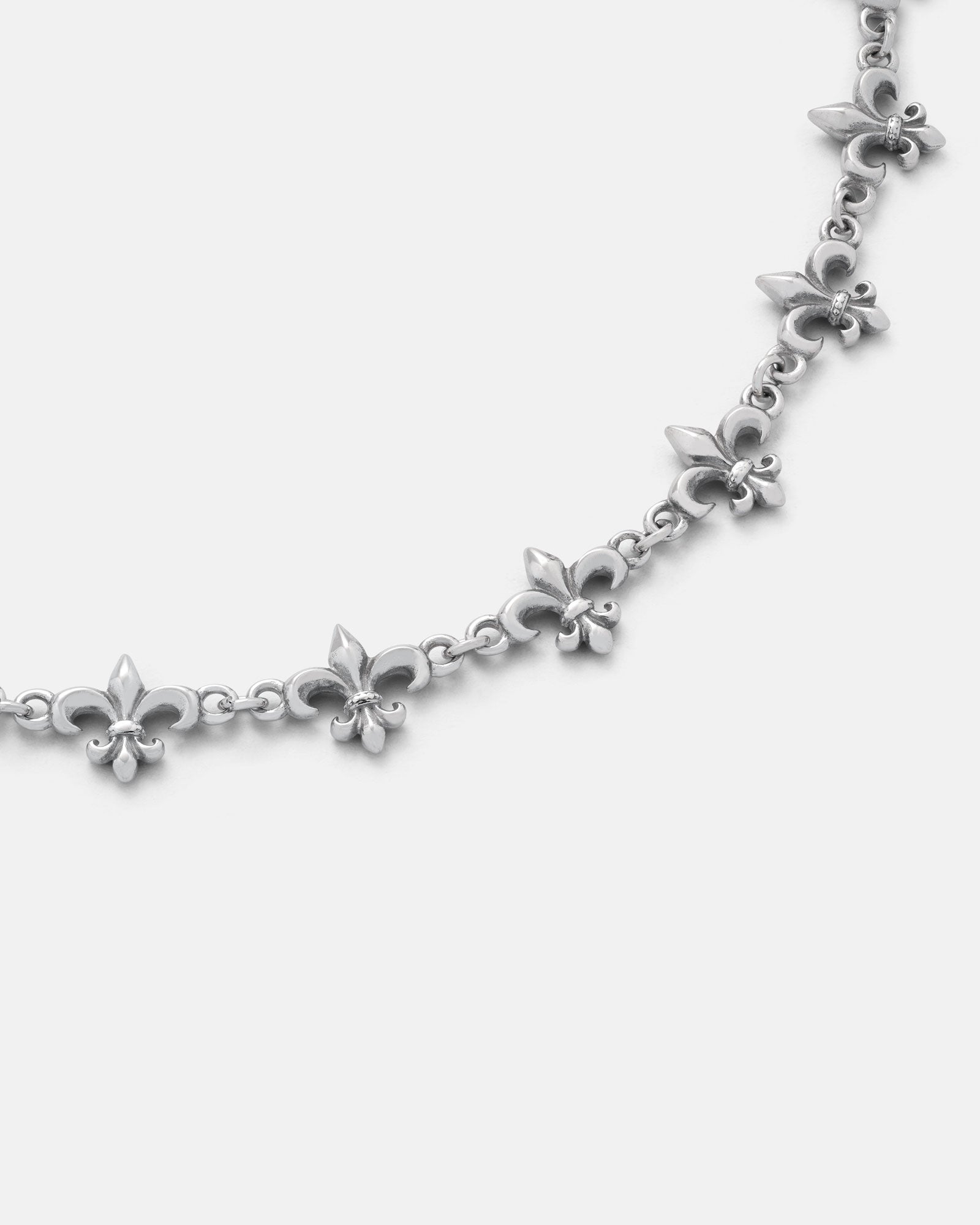 The "Fleur De Lis" 10mm Chain by Statement Collective showcases a repeating pattern of small and large fleur-de-lis charms linked together, displayed on a plain white background.