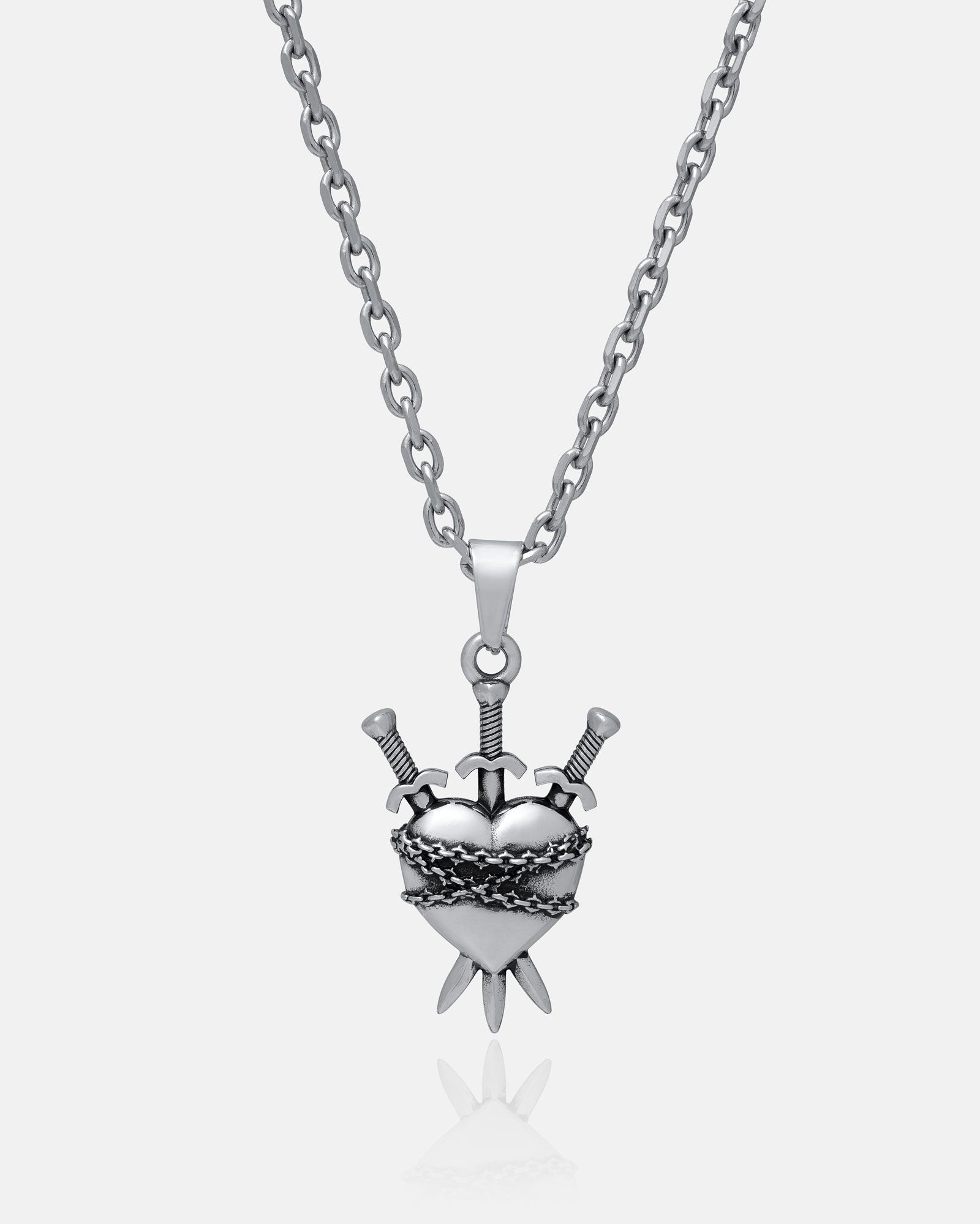 The "3 of Swords" Pendant features a silver chain necklace with a heart-shaped pendant wrapped in barbed wire and pierced by three swords—ideal for tarot jewelry fans. Shown on a plain white background.