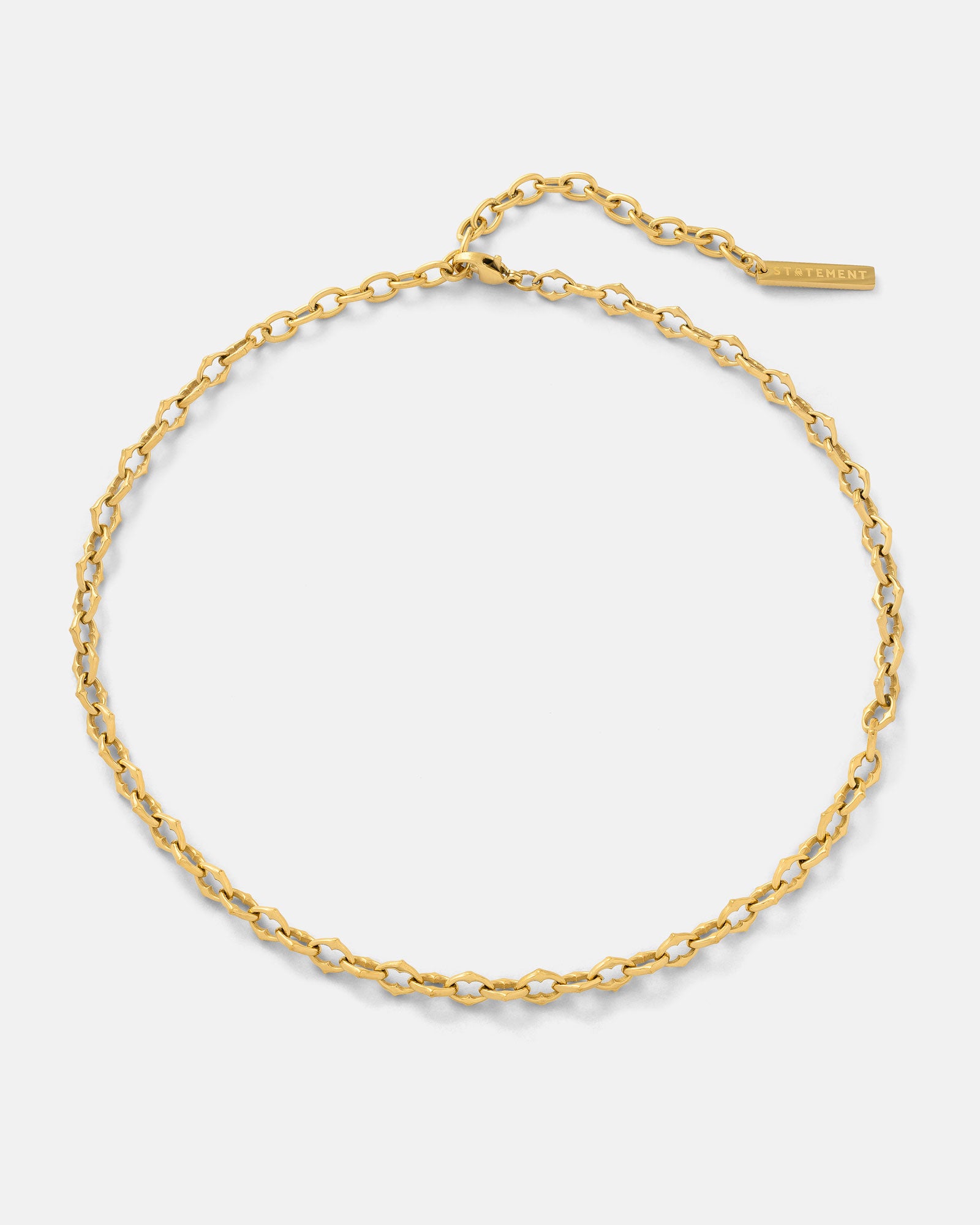 Thin gold spiked chain necklace on a light gray background