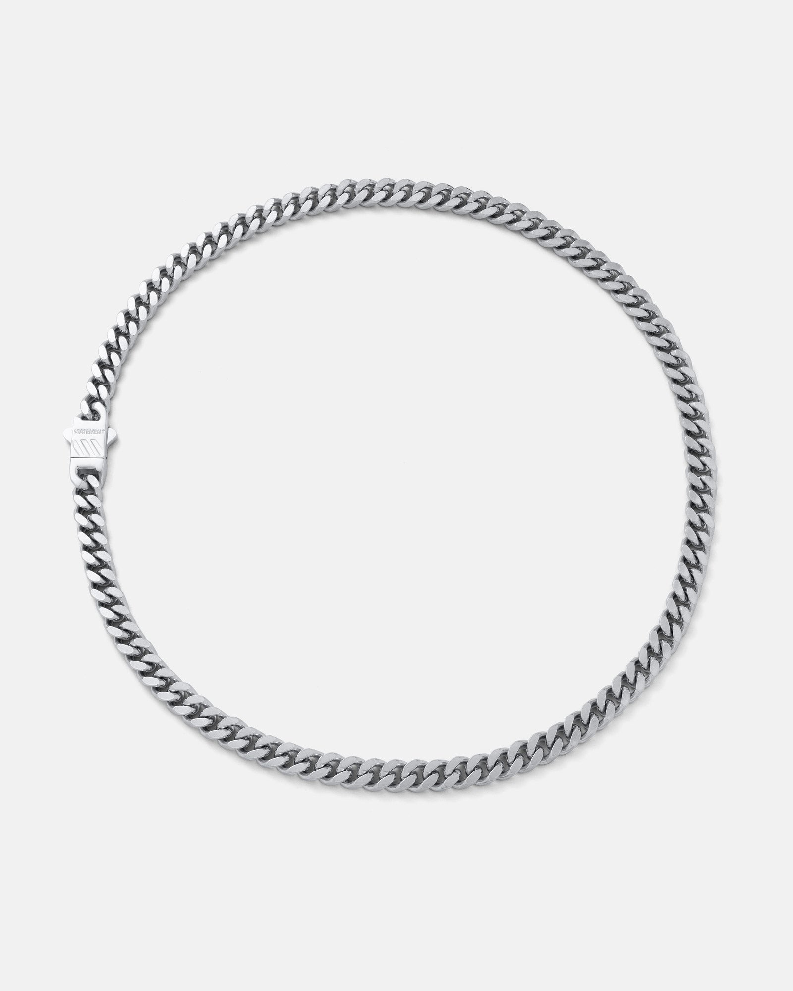 The 6mm Cuban Chain features a sleek, flat silver design with a clasp, shown in a circle on a light gray background. Crafted from stainless steel for lasting shine, this necklace offers durable style.