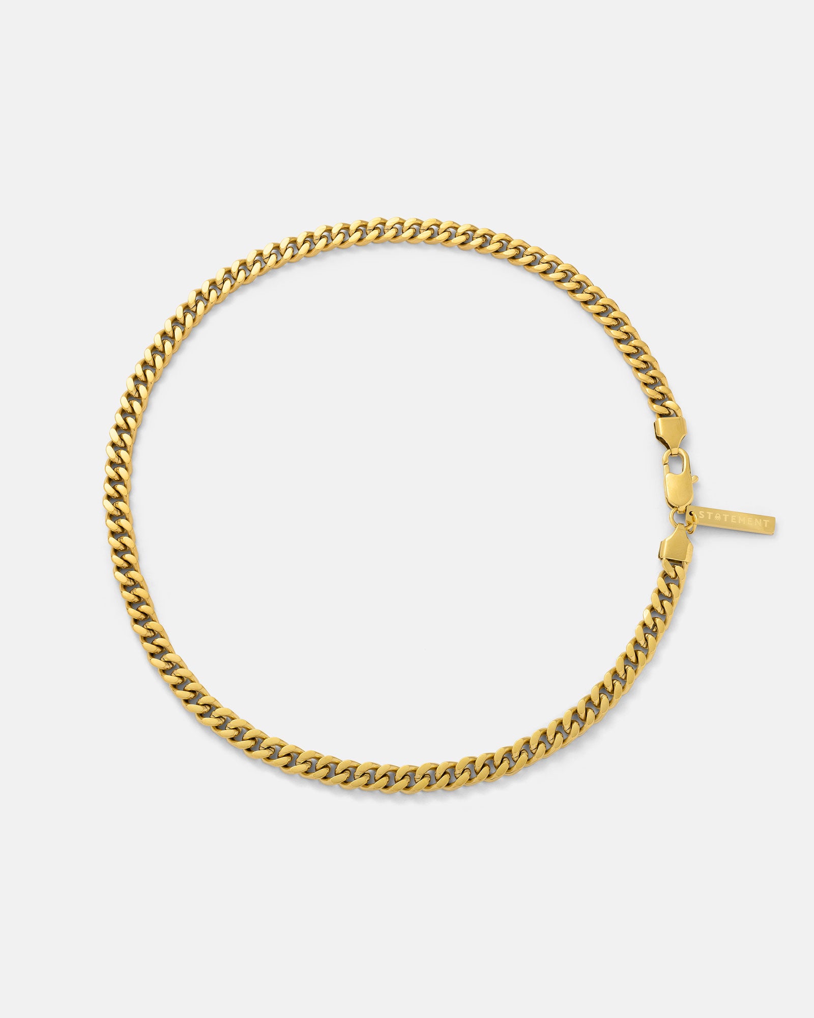 The 6mm Cuban Chain (Gold) is a non-tarnish, 18k gold plated flat curb link necklace with a rectangular tag near the clasp, shown in a circular shape on a plain white background.