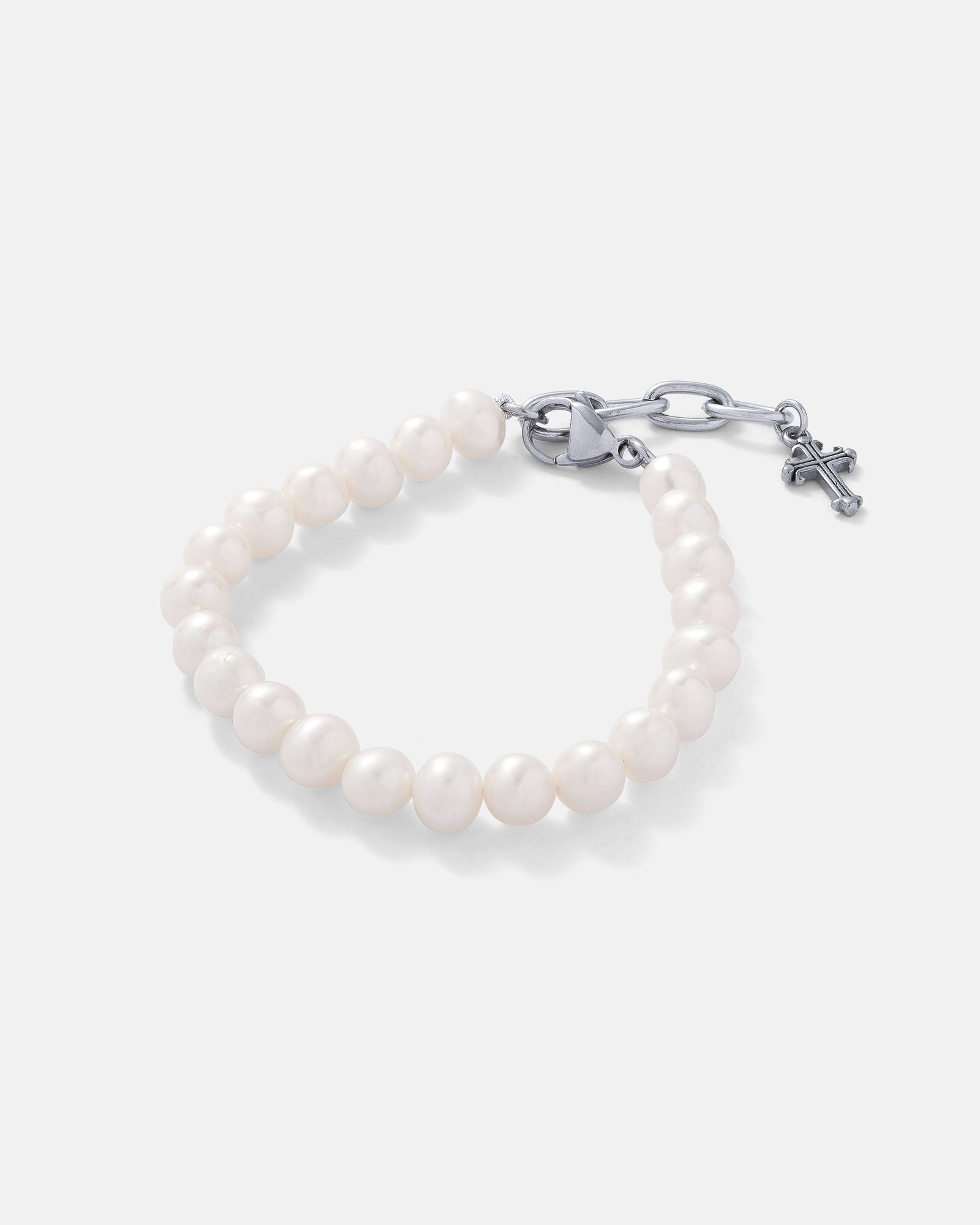 8mm freshwater pearl bracelet with silver clasp and 2.5cm extender that is charmed with a mini silver french cross on the end on grey background.