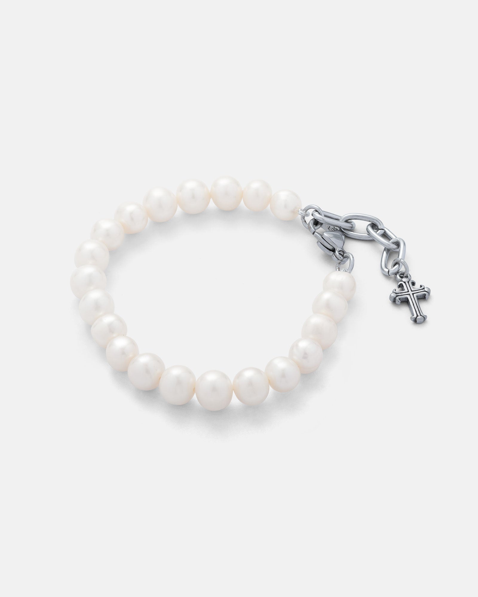 8mm freshwater pearl bracelet with silver clasp and 2.5cm extender that has a mini silver french cross hanging off the end on grey background.