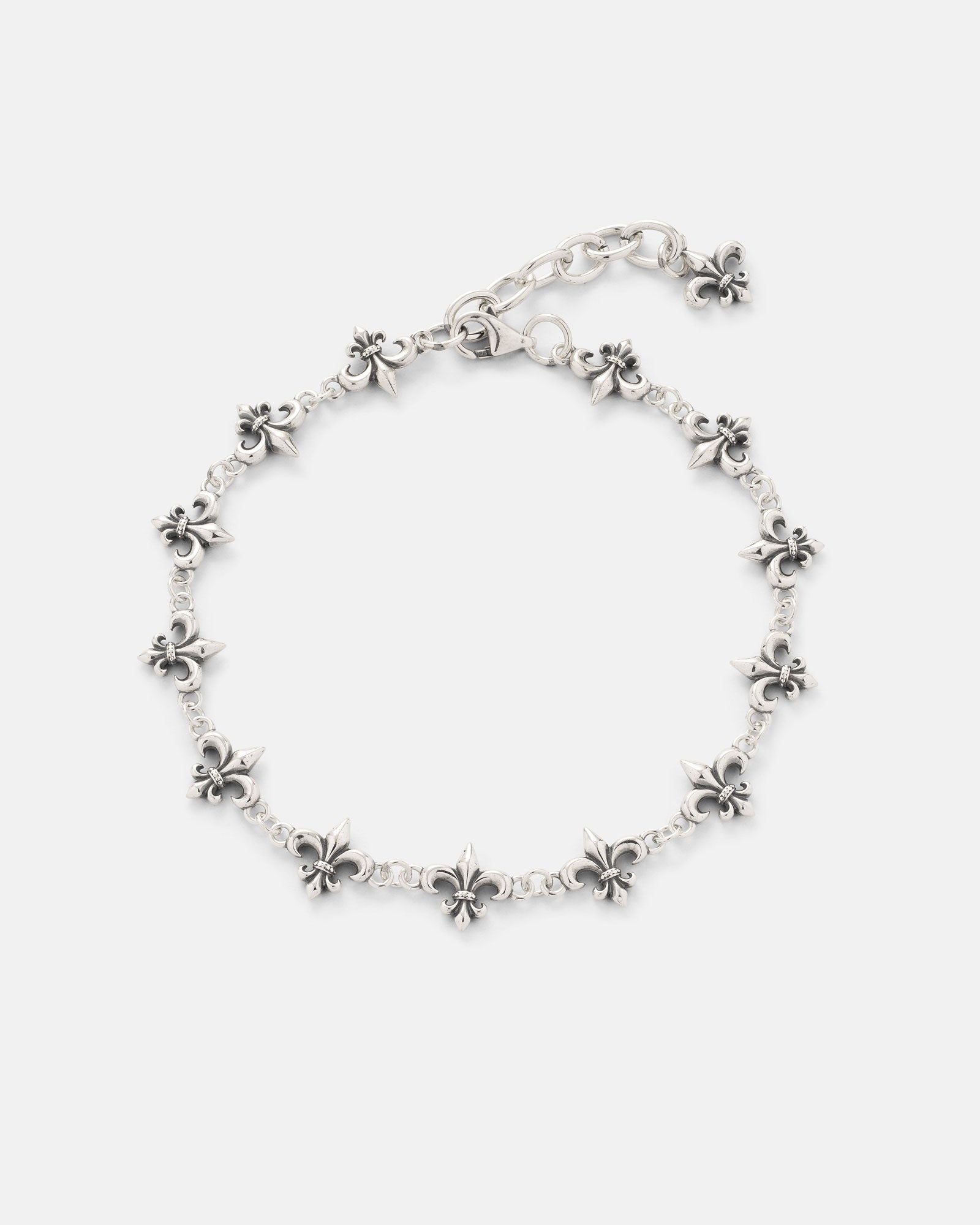 The Statement Collective 925 Sterling Silver "Fleur De Lis" 10mm Bracelet showcases a chain of small, evenly spaced fleur-de-lis charms and features an adjustable clasp, beautifully presented on a plain white background.