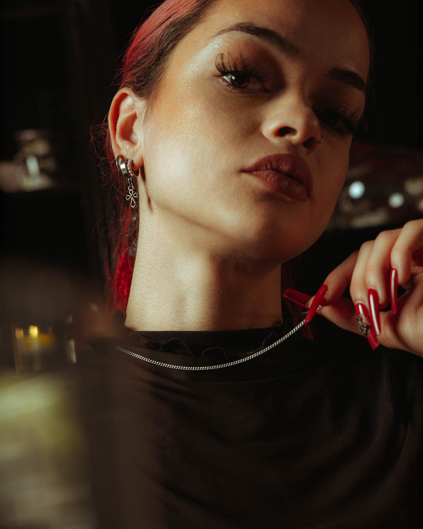 A person with long lashes, bold makeup, and red nails poses confidently in a black top, showcasing the 925 Sterling Silver 2.3mm Curb Chain necklace against a dark, blurred background that highlights this striking daily wear piece.