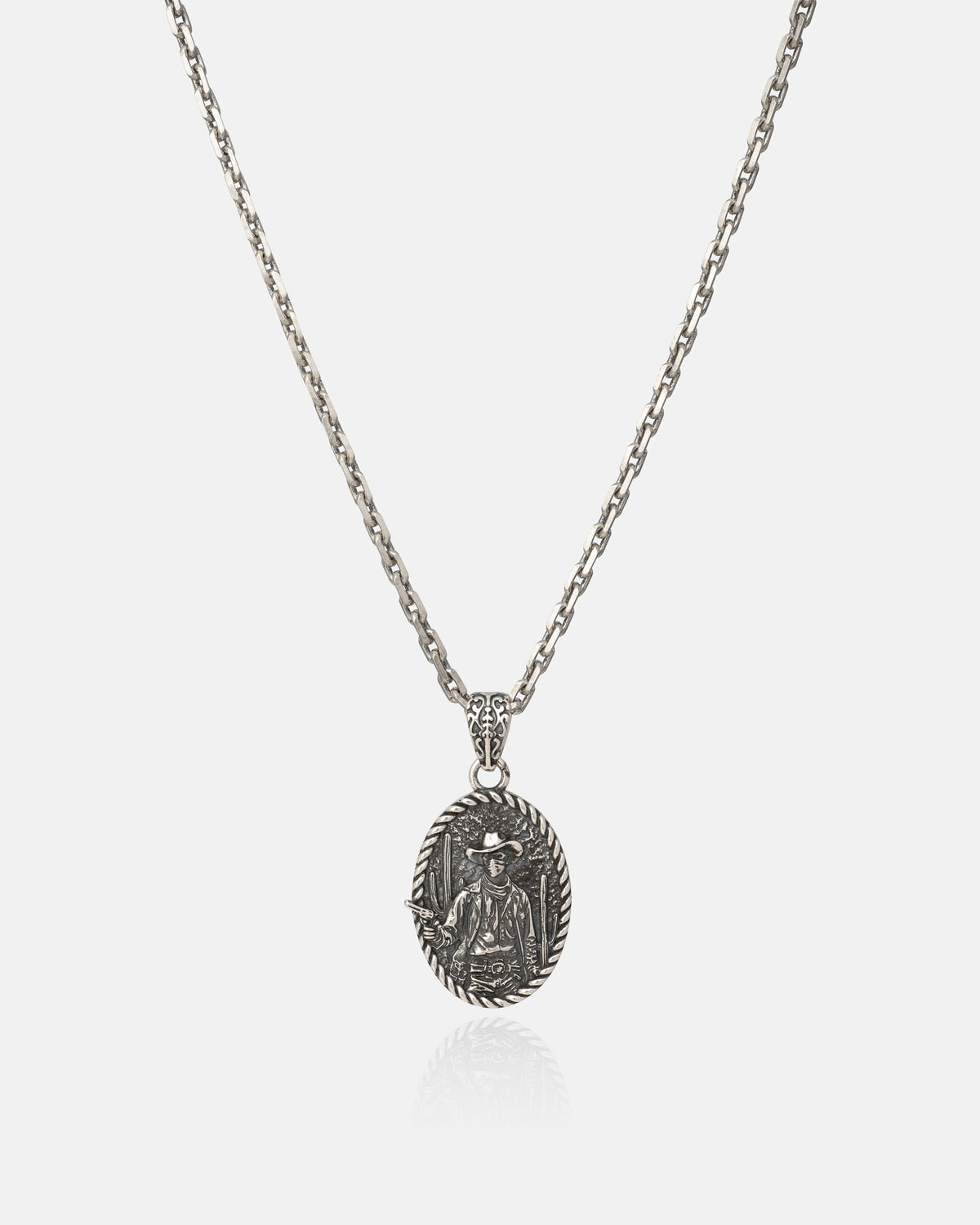 The Statement Collective 925 Sterling Silver "Big Iron" Pendant commands attention with its vintage-inspired design, showcasing a medium-length chain and a striking oval pendant intricately engraved with a person seated beneath a palm tree. Its timeless charm ensures it stands out as a signature addition to any jewelry collection.