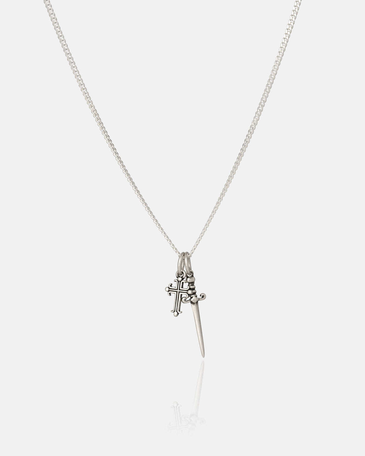 The Statement Collective 925 Sterling Silver Cross & Dagger Necklace features two striking pendants—a detailed cross and a sleek pointed dagger—suspended from a fine sterling silver chain. Photographed against a clean white background, this bold piece of rock jewelry brings edgy style to any outfit.