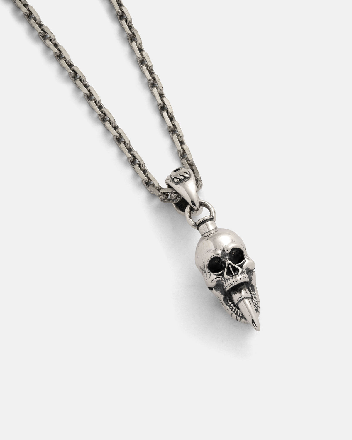 The 925 Sterling Silver Mini "Bite the Bullet" Pendant by Statement Collective hangs from a sleek silver chain, showcasing an intricately detailed skull with a pointed, textured lower jaw—an ideal piece of bold rock jewelry—displayed against a plain white background.