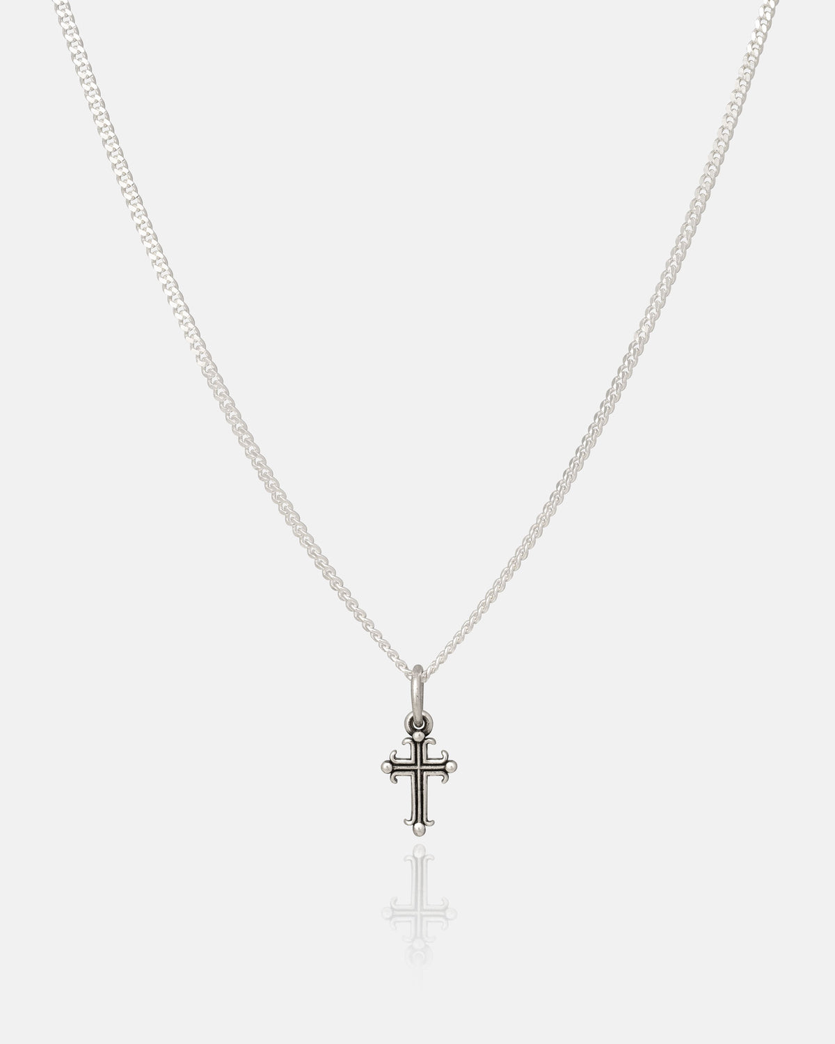The Statement Collective 925 Sterling Silver Mini French Cross Pendant features a small ornate cross on a silver chain, elegantly showcased against a plain white background.