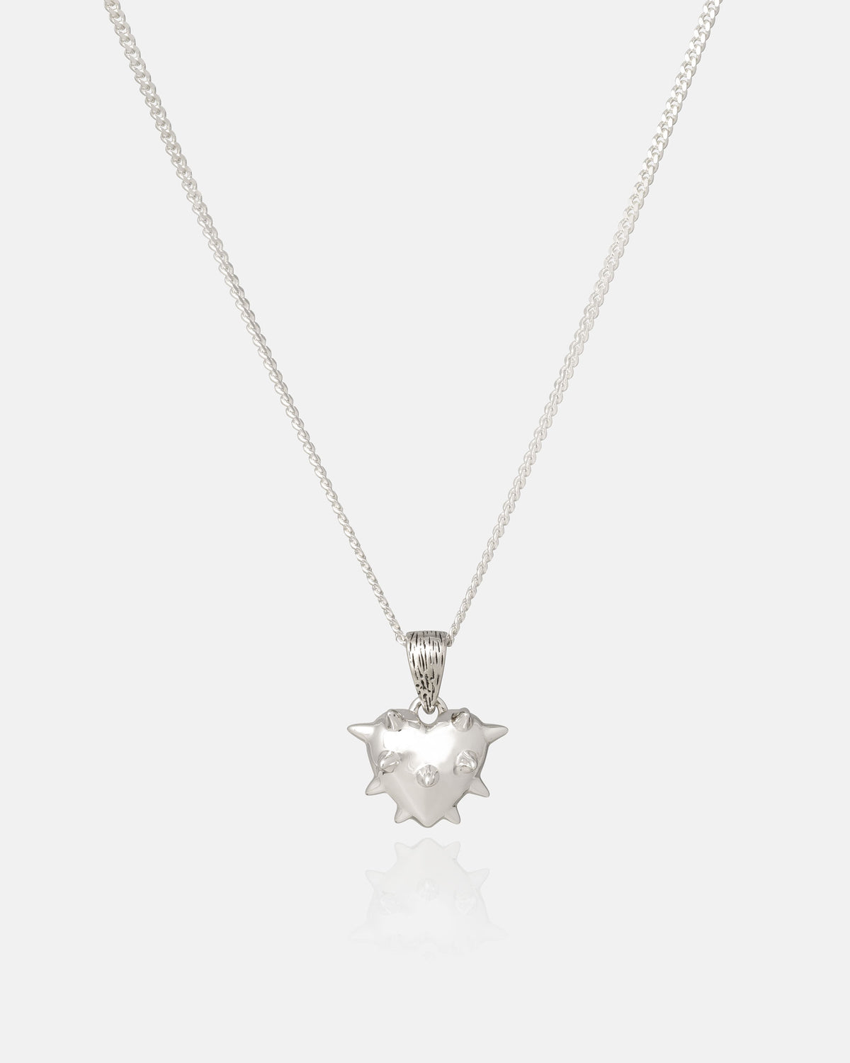 The 925 Sterling Silver Mini "Love Hurts" Pendant by Statement Collective is an edgy piece of rock jewelry featuring a thin silver chain and a shiny, spiky heart-shaped pendant adorned with two small embedded gems, beautifully displayed against a plain white background.