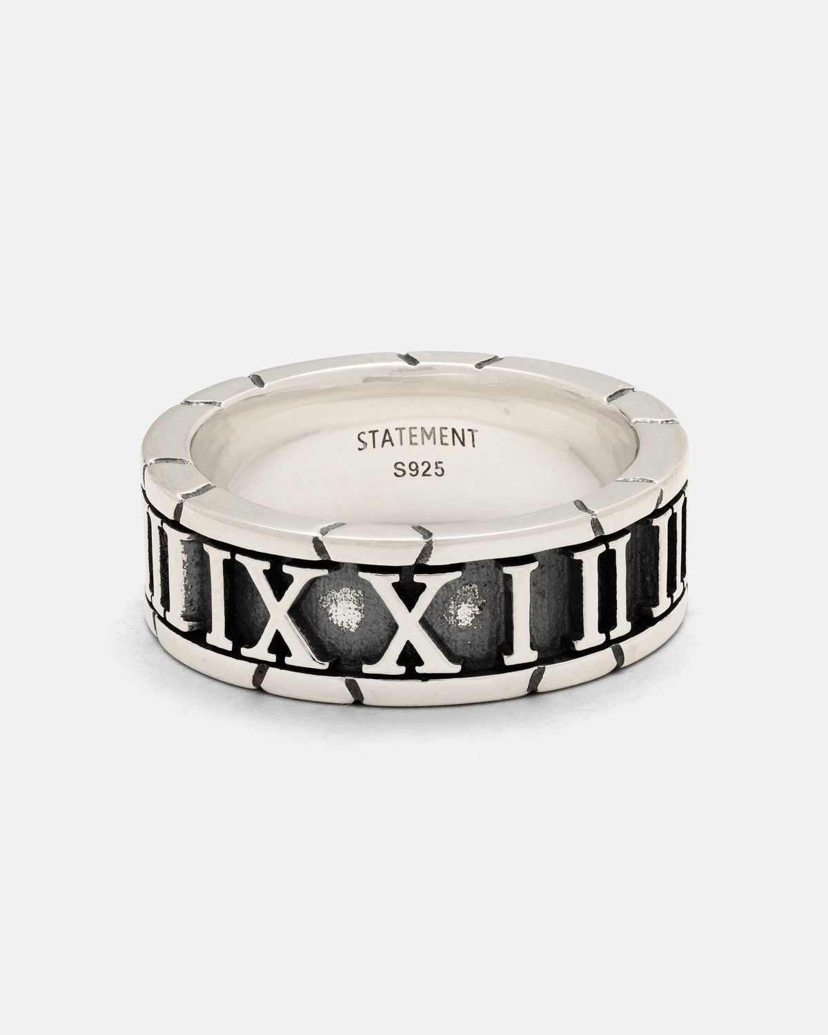 The 925 Sterling Silver Numerals Ring by Statement Collective features boldly outlined Roman numerals encircling the band against a darkened background. Handcrafted for rustic elegance, the inner band is stamped with STATEMENT S925.