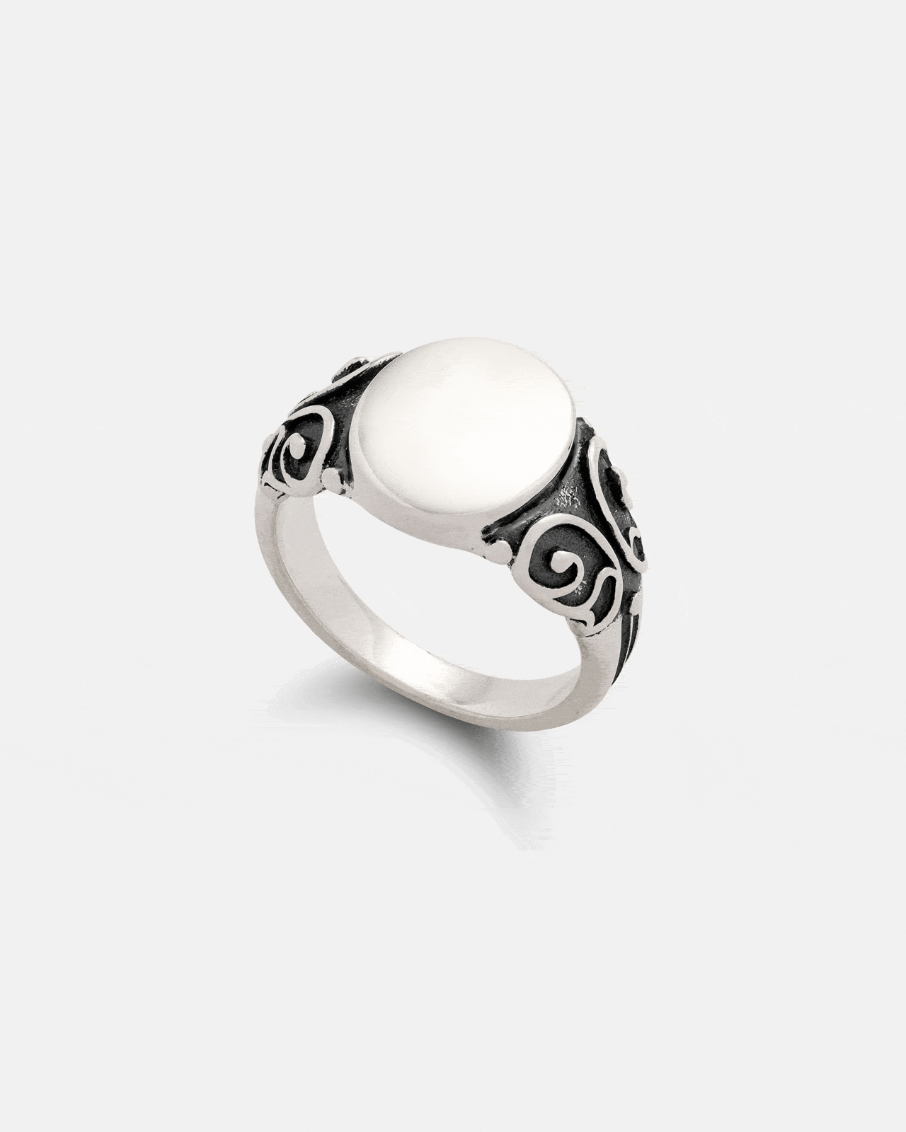 The 925 Sterling Silver Mini Oval Scroll Signet Ring by Statement Collective features a smooth white stone center and ornate swirling black antique-style detailing on the band.
