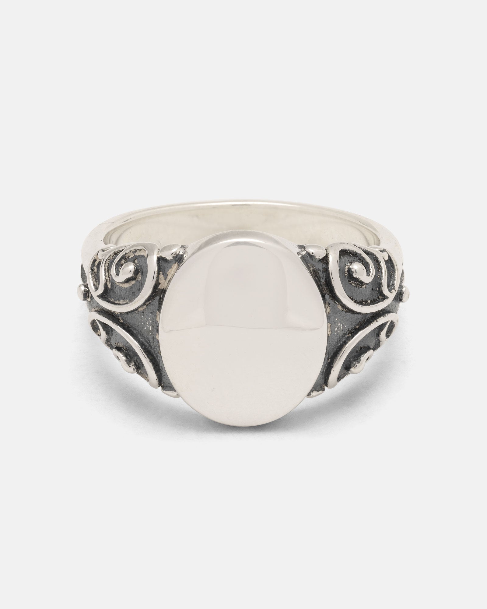 A handcrafted 925 Sterling Silver Mini Oval Scroll Signet Ring by Statement Collective, featuring a smooth, flat oval center and ornate, swirling scroll designs along the band, photographed against a plain white background.