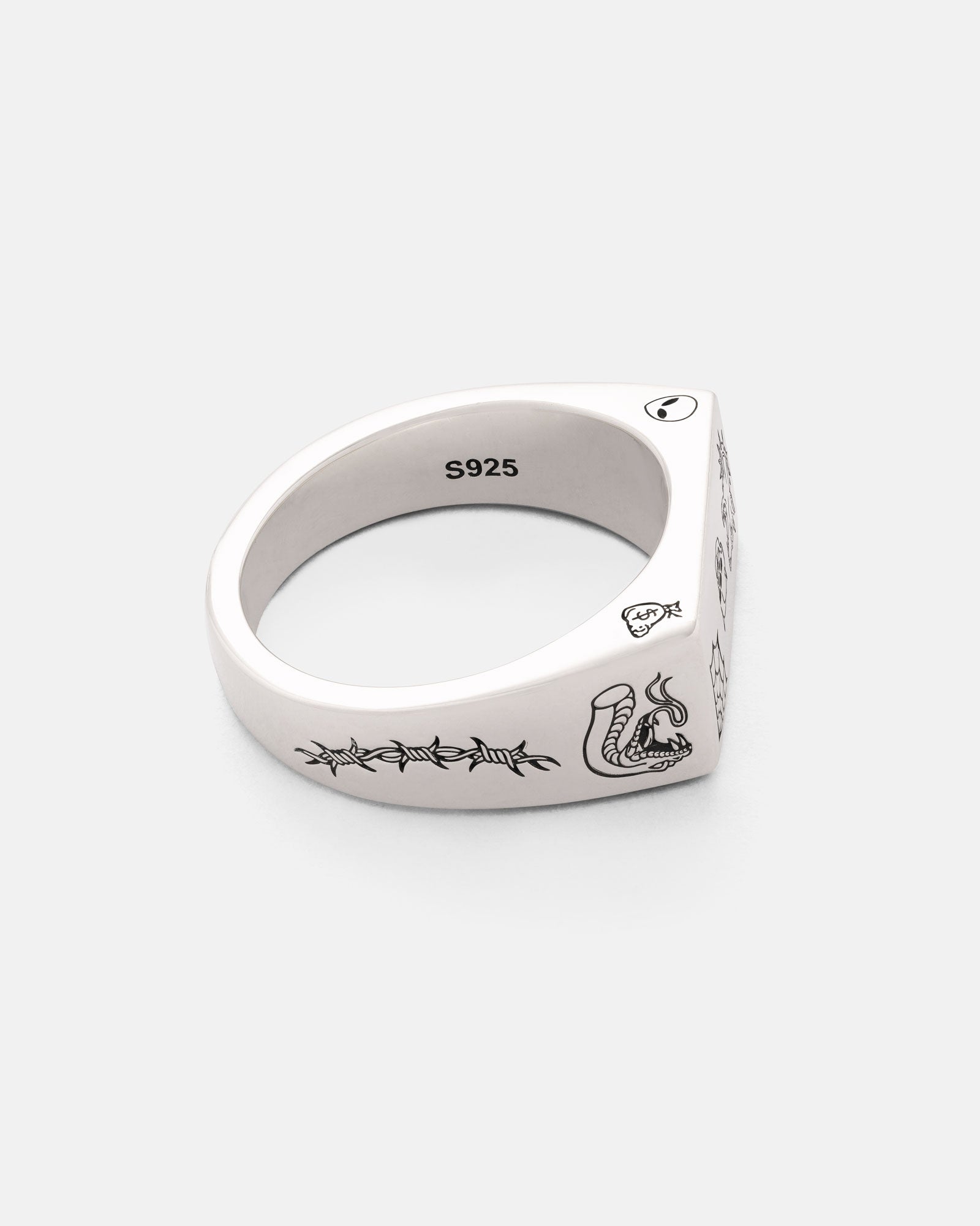 The Statement Collective 925 Sterling Silver Tattoo Signet Ring features engraved snake, barbed wire, and heart designs, plus an S925 mark on the inner band, shown against a plain white background.