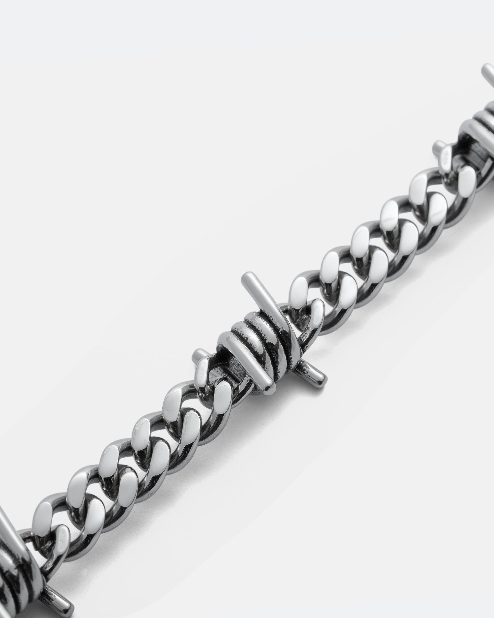Close-up of the 9mm Barbed Wire Cuban Chain bracelet, featuring a curb link design with evenly spaced metallic barbed wire accents.