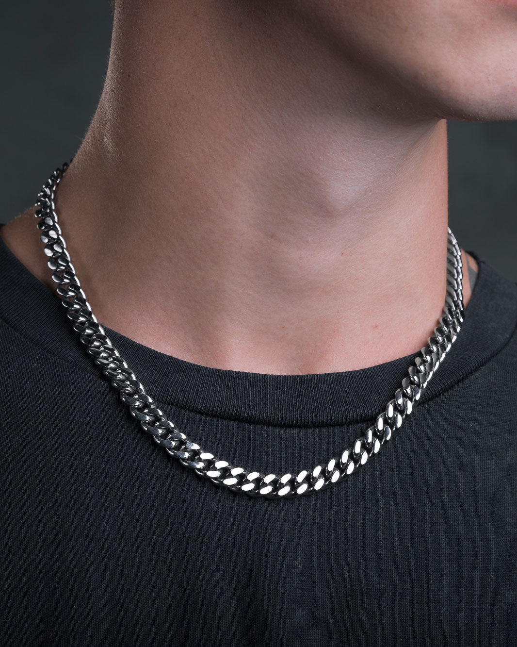 A close-up of a person wearing the 9mm Cuban Chain and a black shirt, showing only the lower half of their face and neck against a dark background.