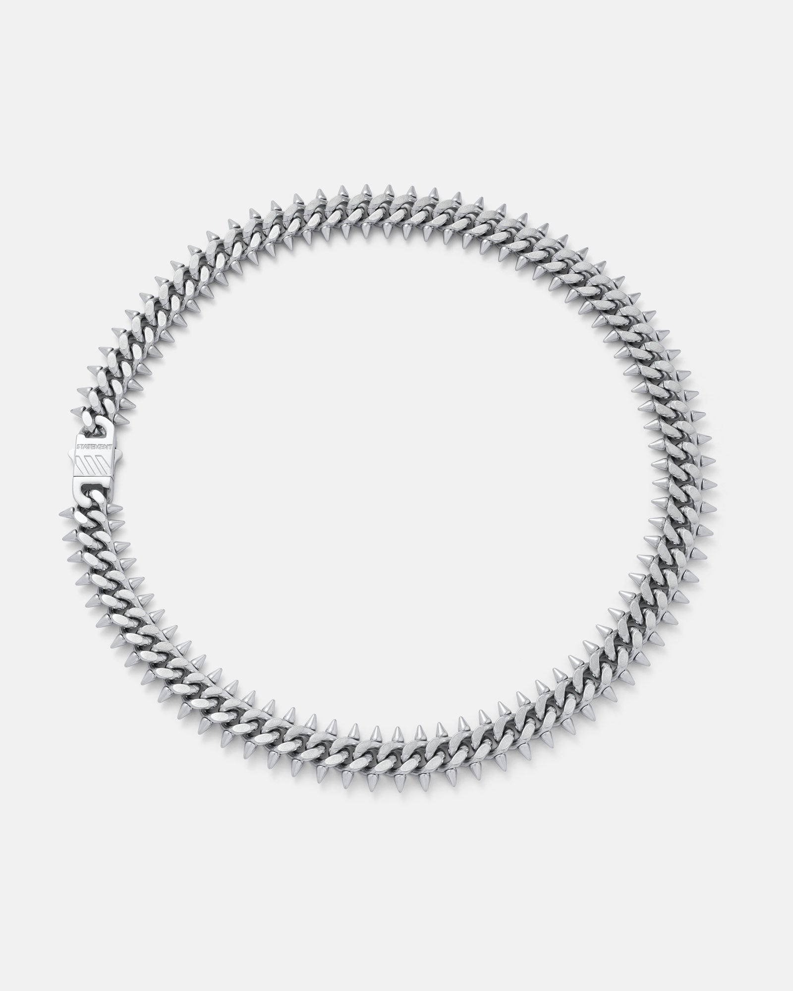 The "Screwed Up" Spiked Cuban Chain is a silver necklace with closely arranged pointed spikes in a circular pattern, shown against a plain white background.