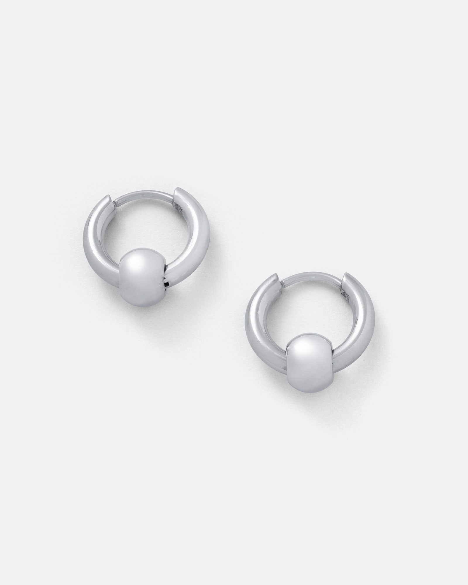 Ball Hoop Earrings: Small, silver hoops with smooth bead accents, crafted from hypoallergenic stainless steel, shown on a plain light gray background.