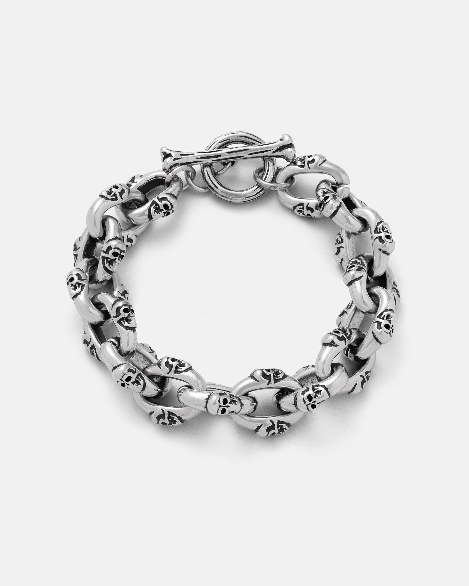 The "Boneyards" Skull Bracelet by Statement Collective is a chunky 316L stainless steel piece with interconnected links, each featuring small skulls. This men’s accessory has a circular toggle clasp and is shown on a plain light background.