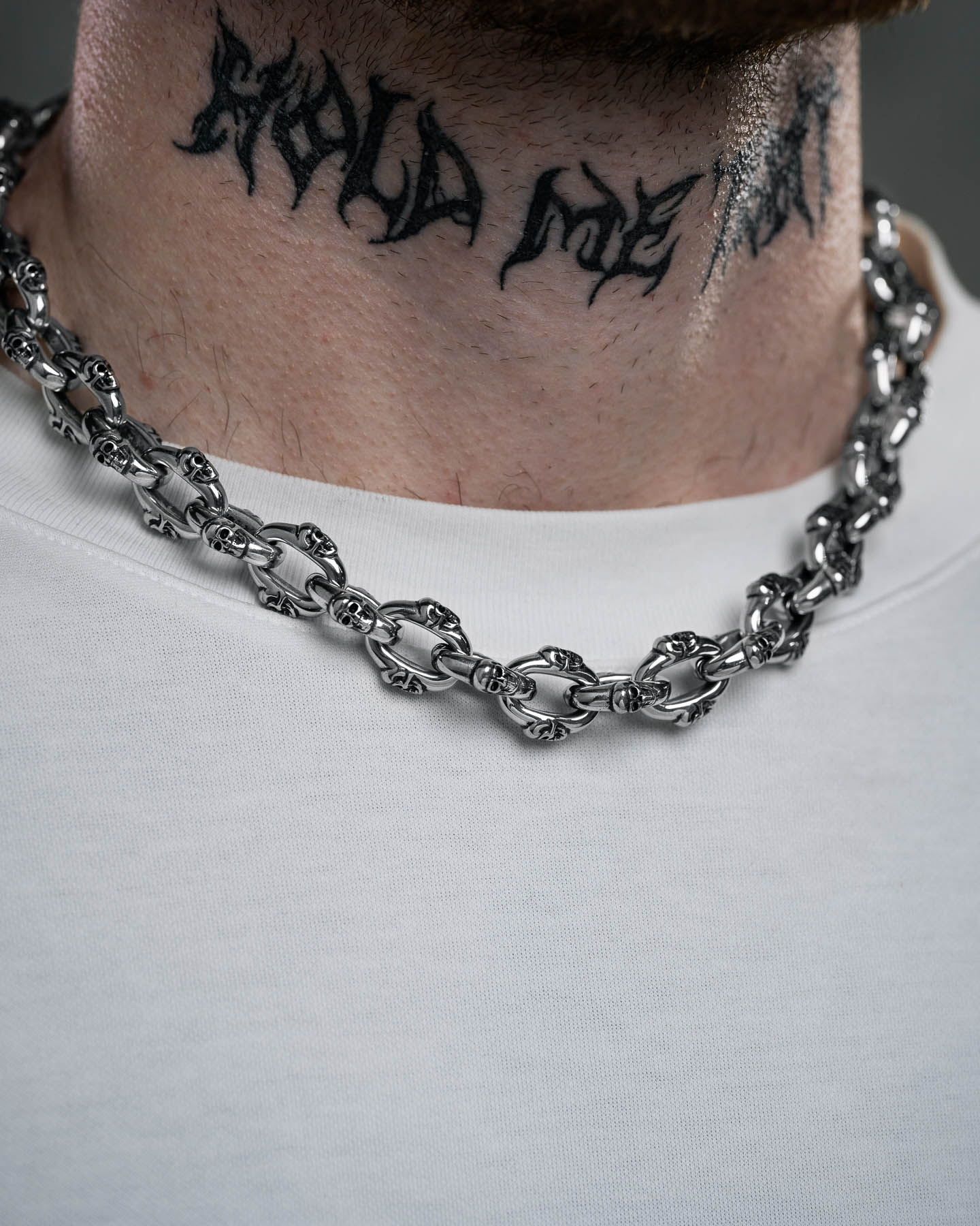 A close-up of a person's neck shows a black script tattoo and the bold "Boneyards" Skull Chain necklace, paired with a plain white shirt.